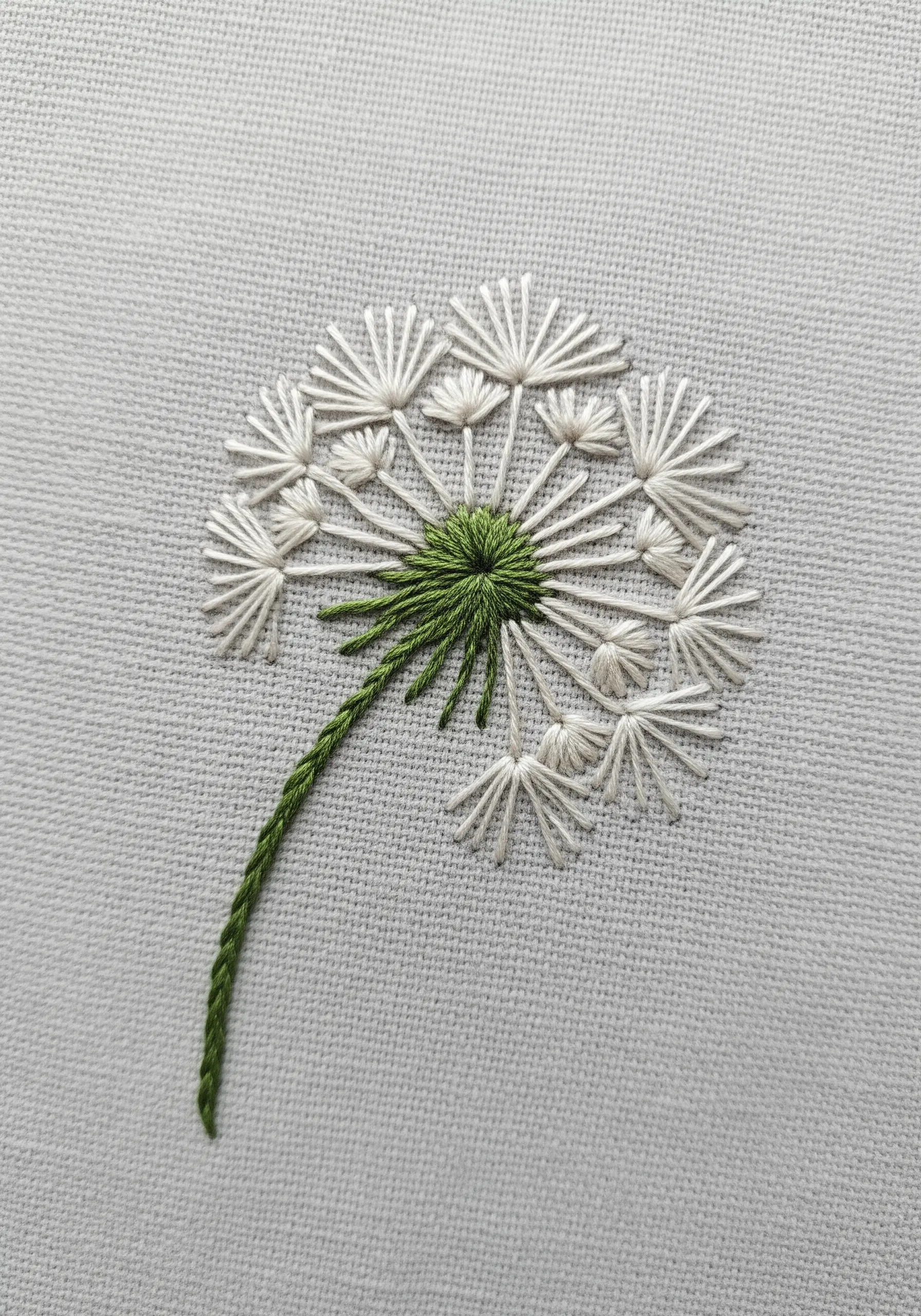 A delicate dandelion seed head made with white radiating straight stitches.
