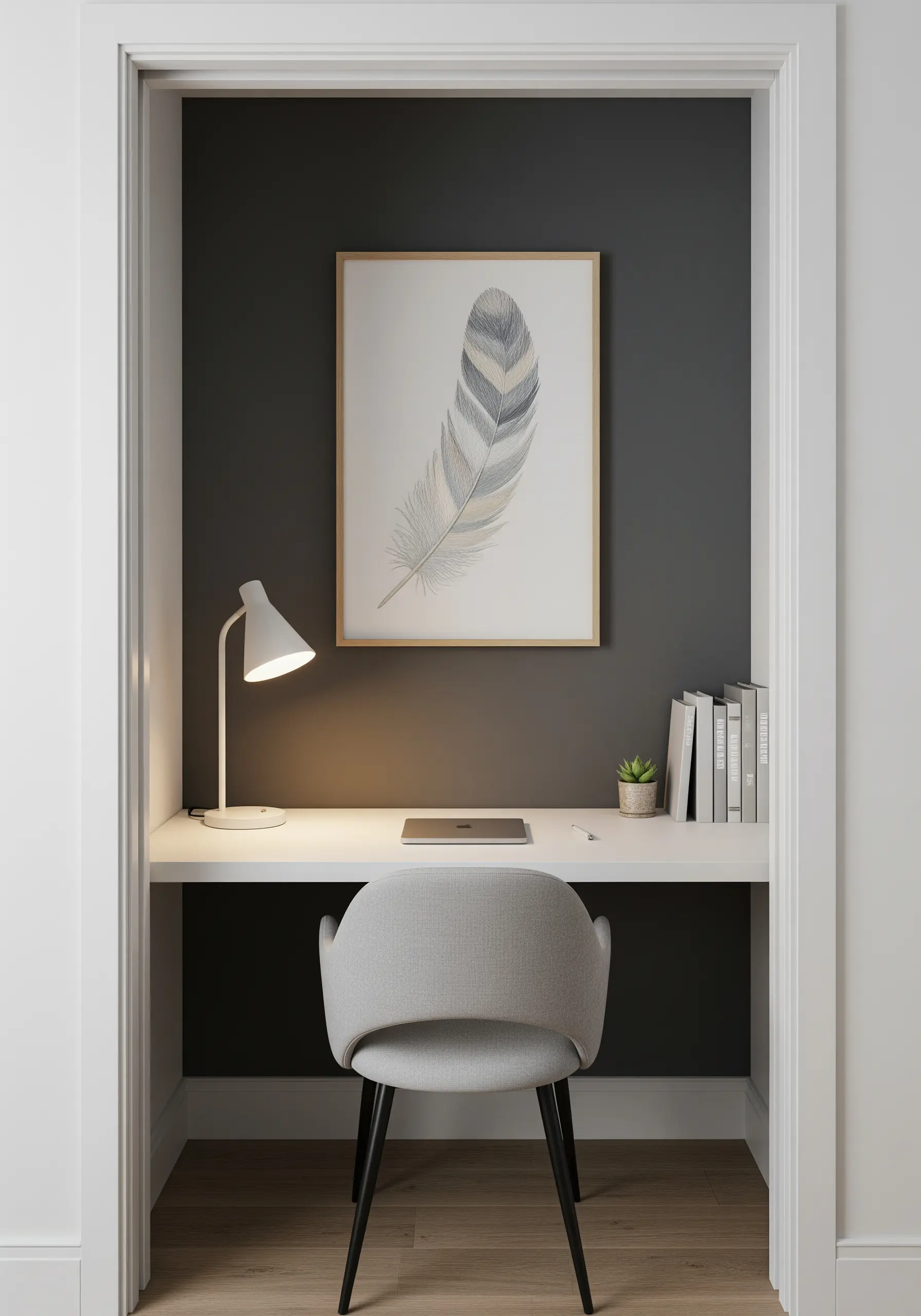 A framed embroidery of a single, delicately shaded feather hanging in a small office nook