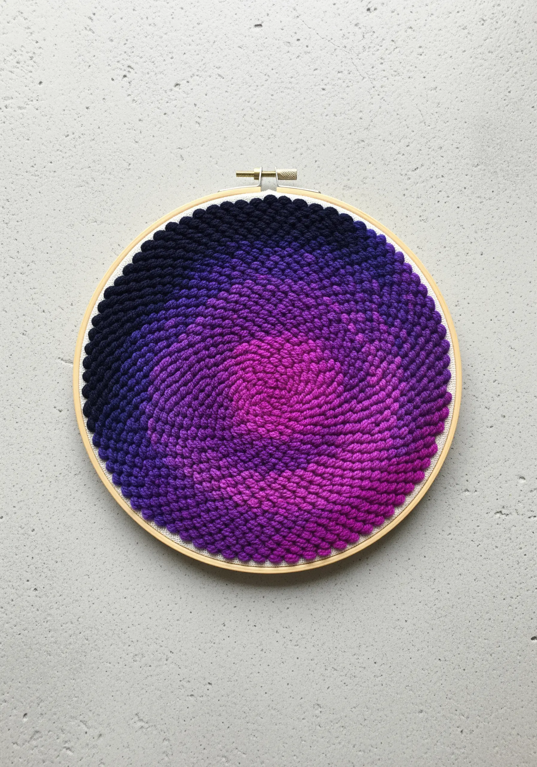 Embroidery hoop filled with a spiral of French knots in a purple-to-pink gradient.