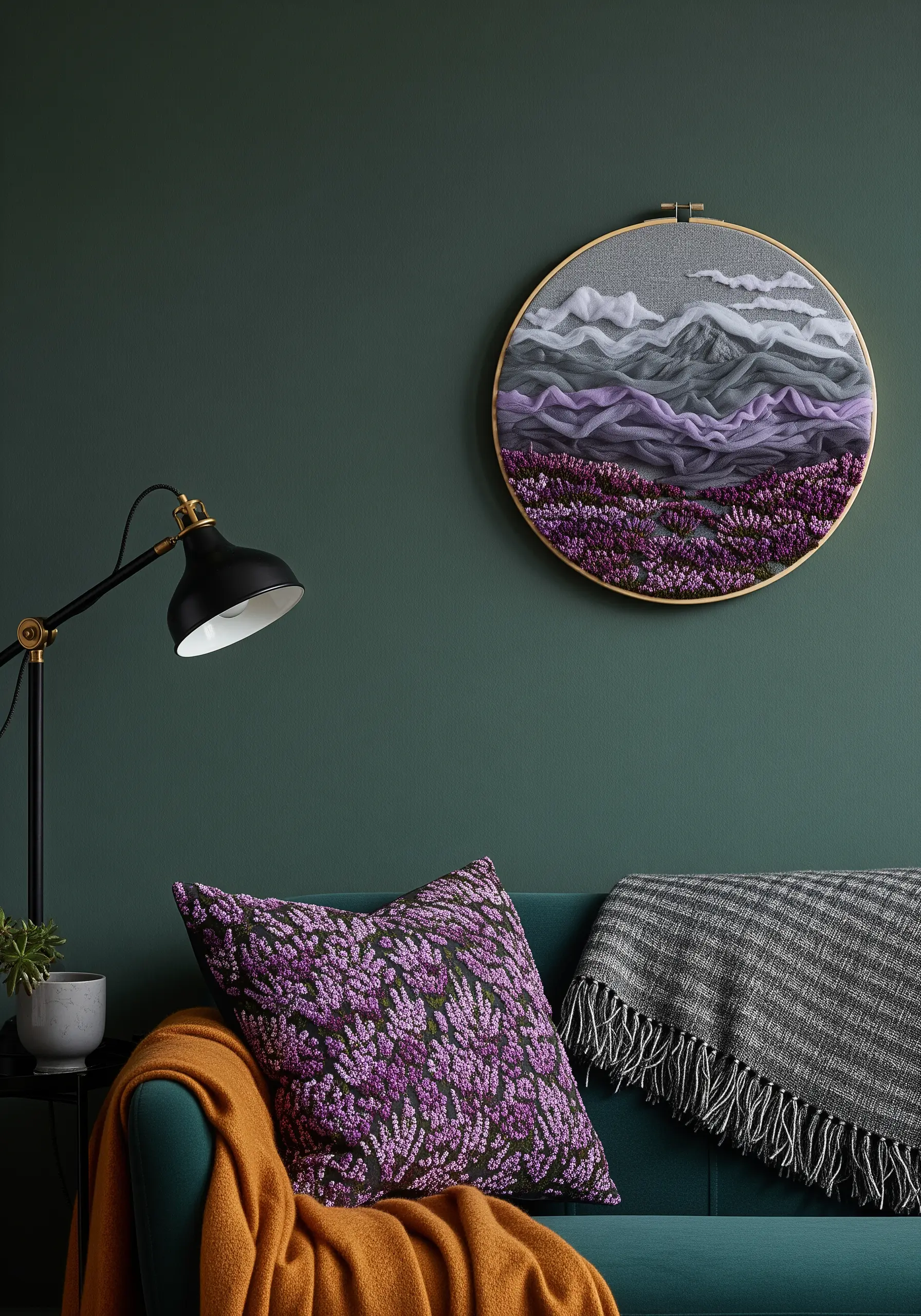 Embroidery of a purple lavender field in front of mountains, displayed on a dark green wall.