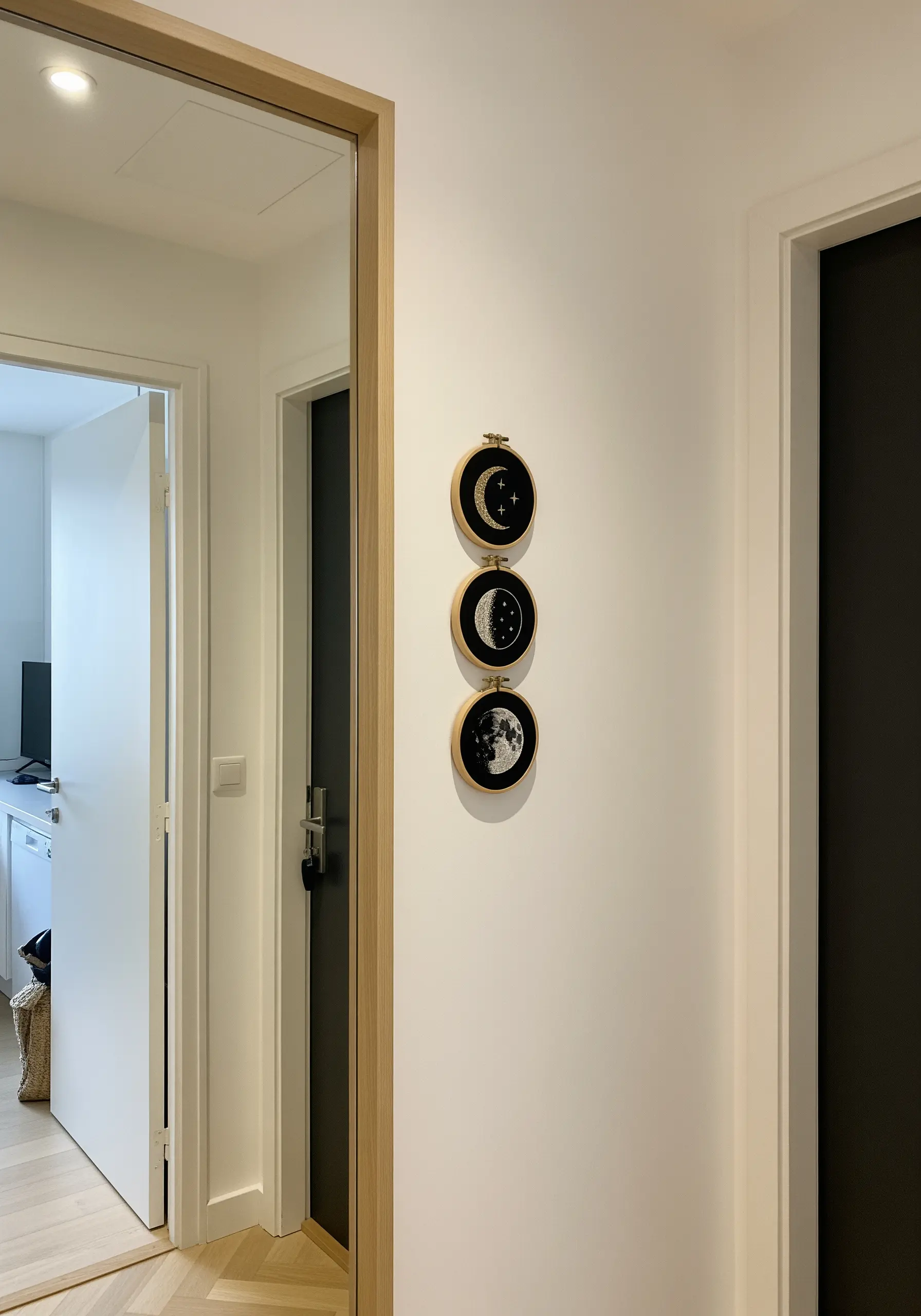 A vertical trio of embroidery hoops showing the phases of the moon on black fabric