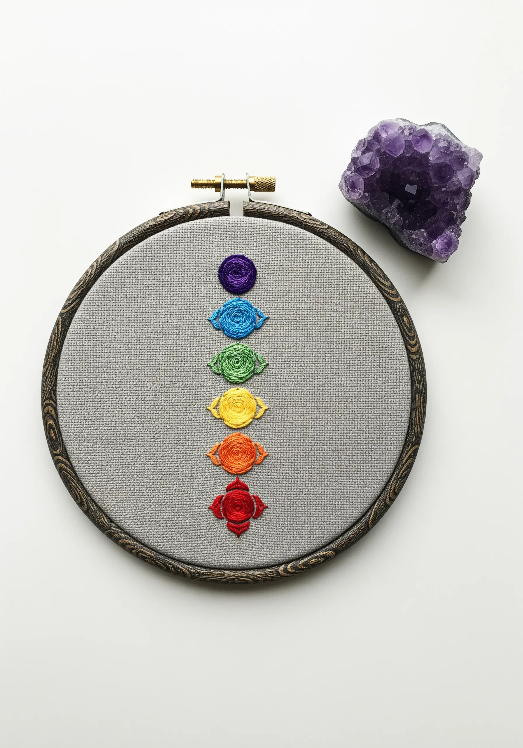 A vertical line of seven small, colorful embroidered spirals representing the chakras.
