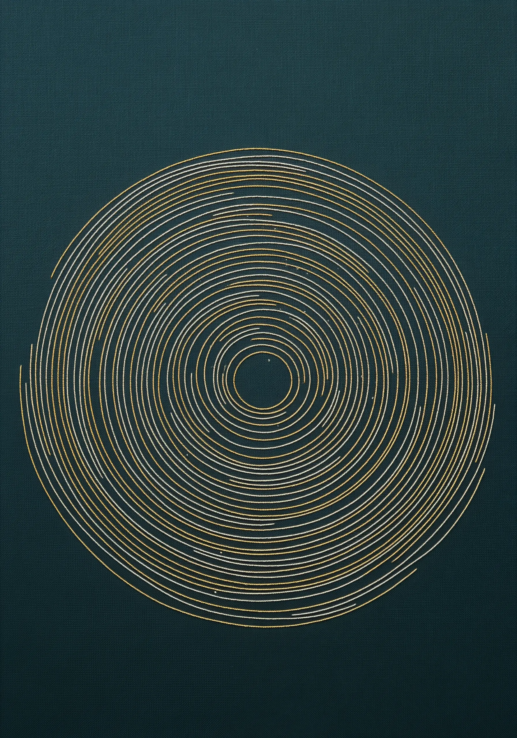 Abstract embroidery of concentric circles in gold and white thread on dark green fabric.