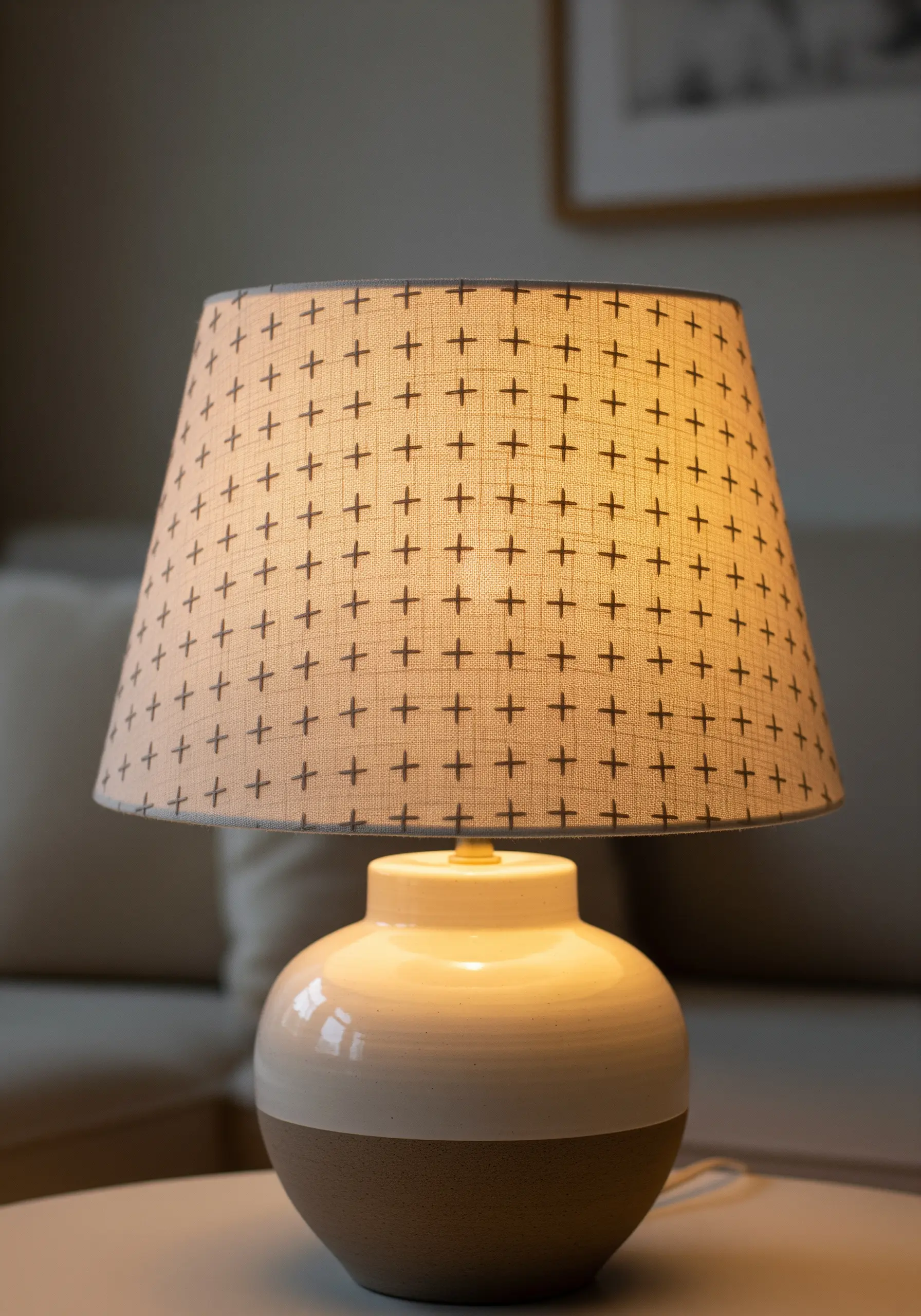 A fabric lampshade with a repeating pattern of small, hand-stitched plus signs.
