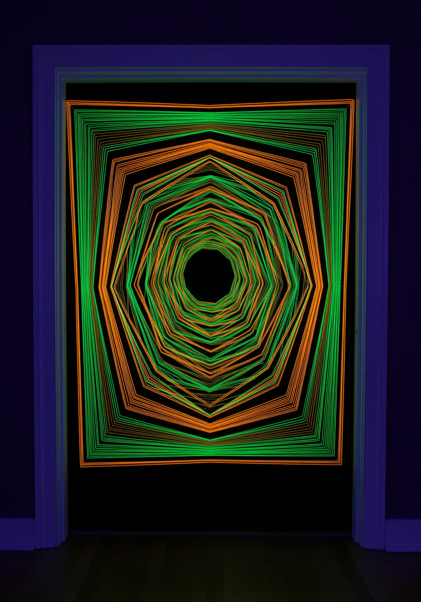 Neon green and orange threads stretched in a doorway create a glowing, geometric tunnel effect.