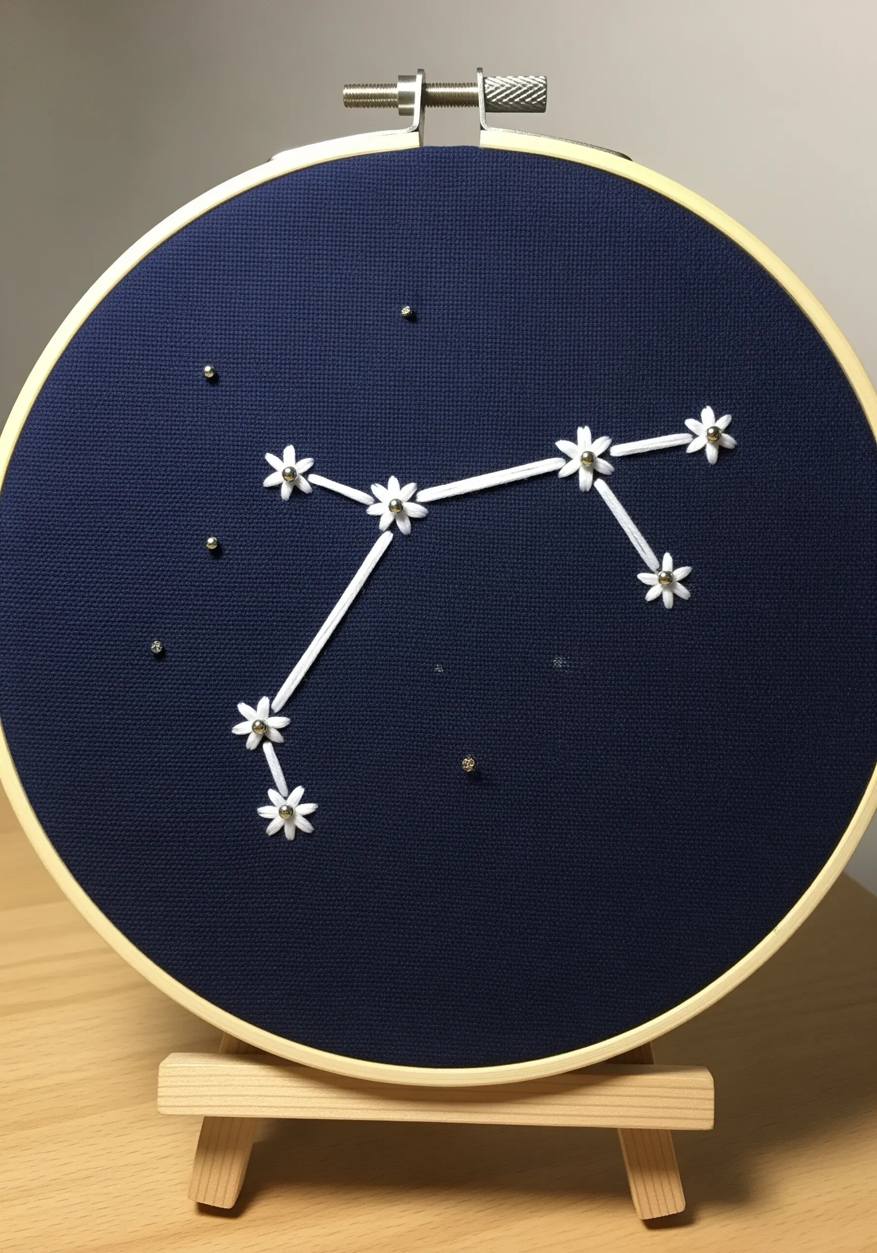 A zodiac constellation stitched on dark blue fabric, with lazy daisy stitches for stars.