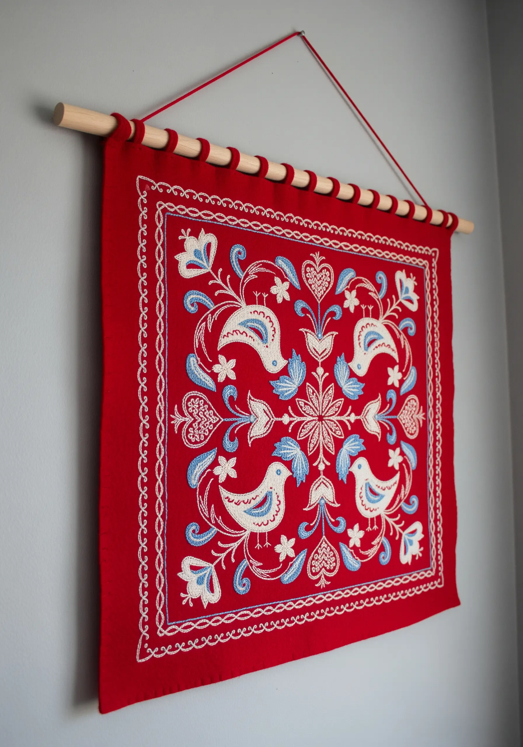 Symmetrical folk art embroidery with birds and flowers in red, white, and blue.