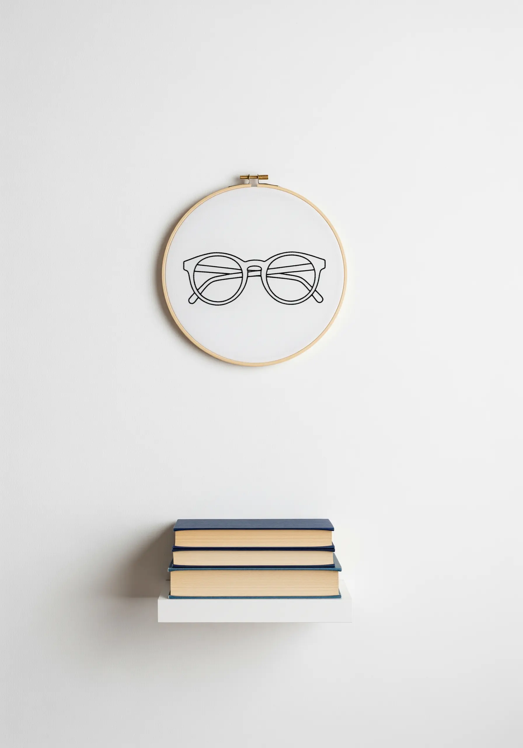 A minimalist outline of a pair of eyeglasses embroidered in black thread.