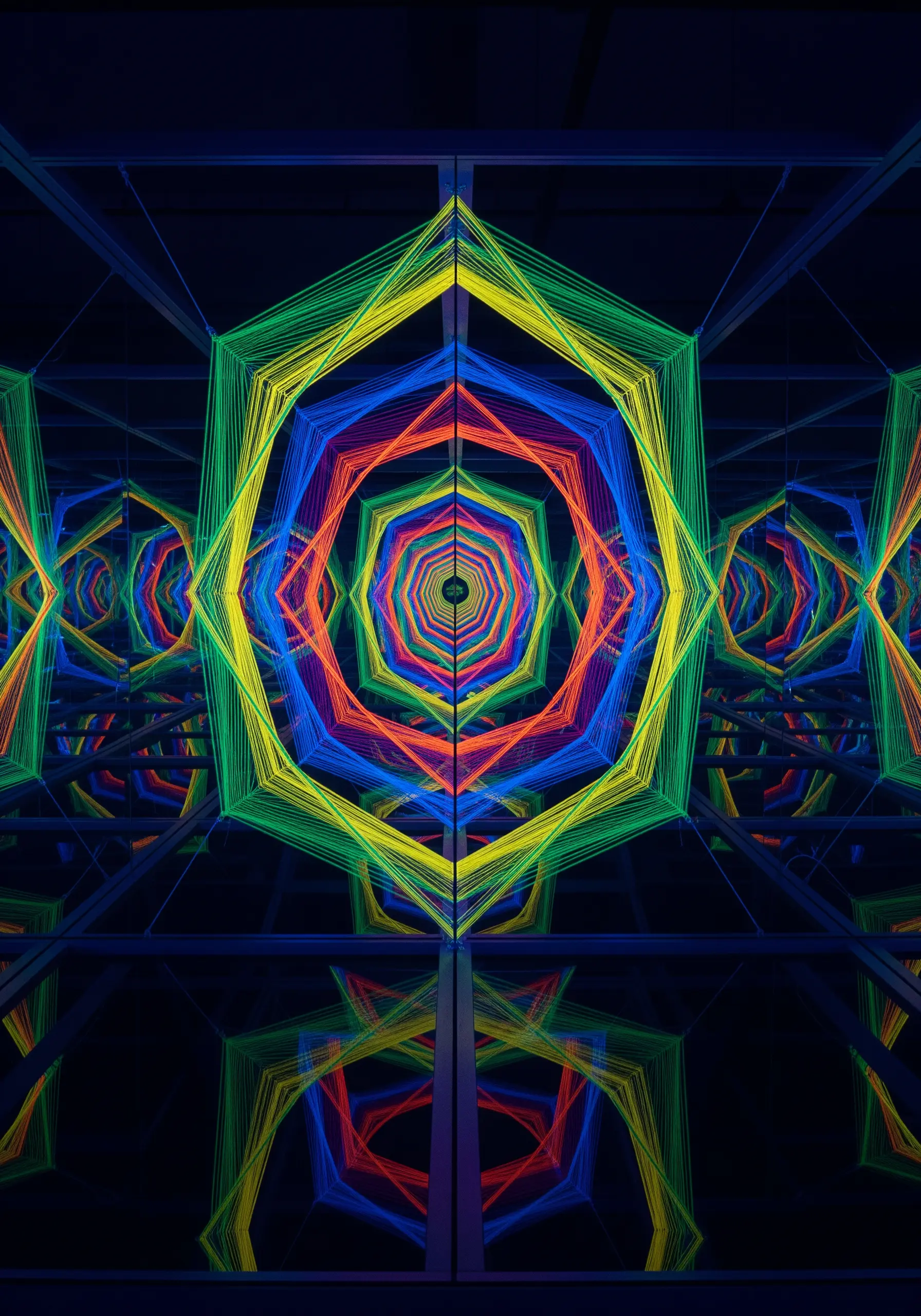 A geometric tunnel of rainbow threads is endlessly reflected in mirrors, creating an infinite illusion.