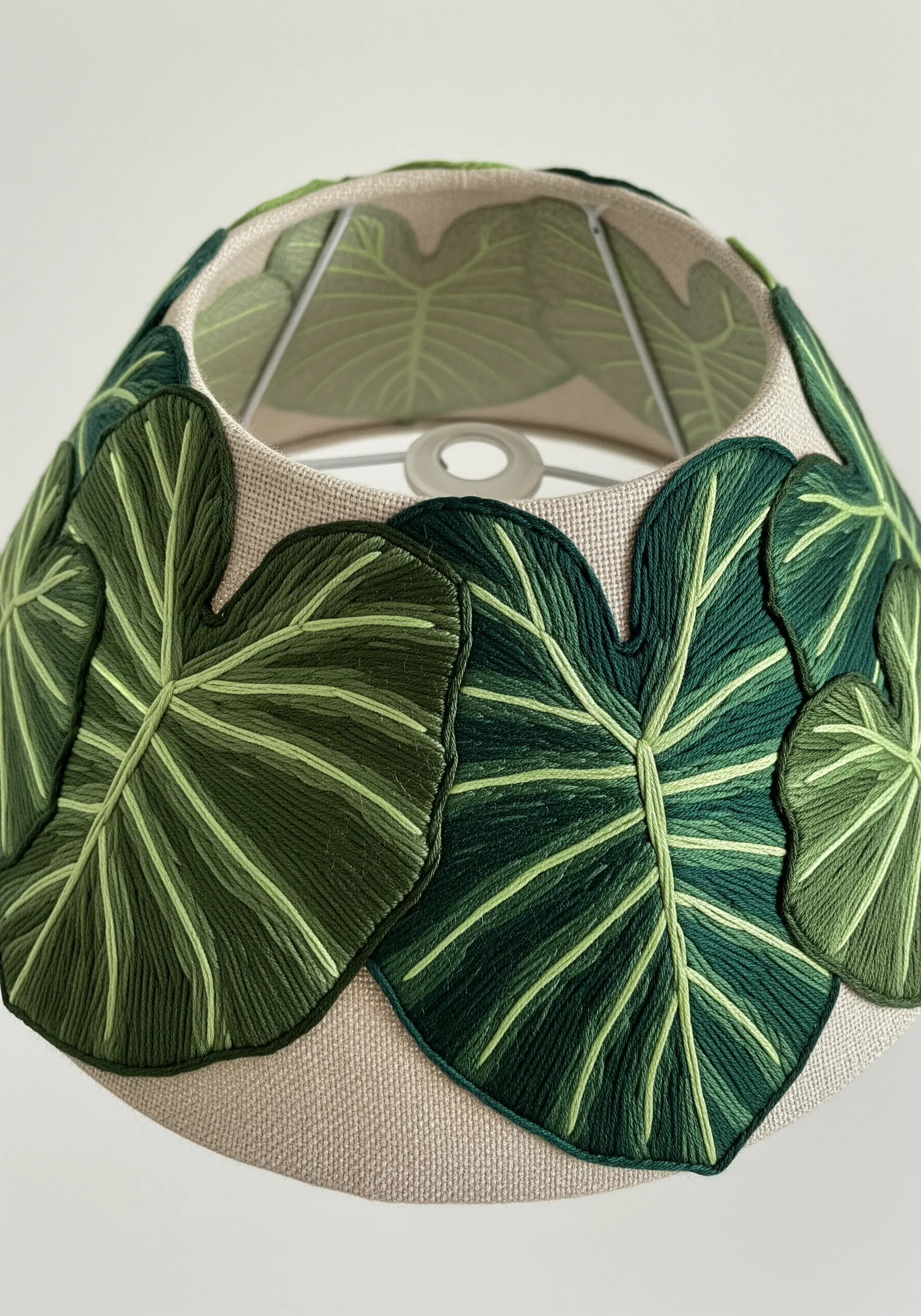 Large, embroidered green leaves cut out and appliquéd onto a fabric lampshade.