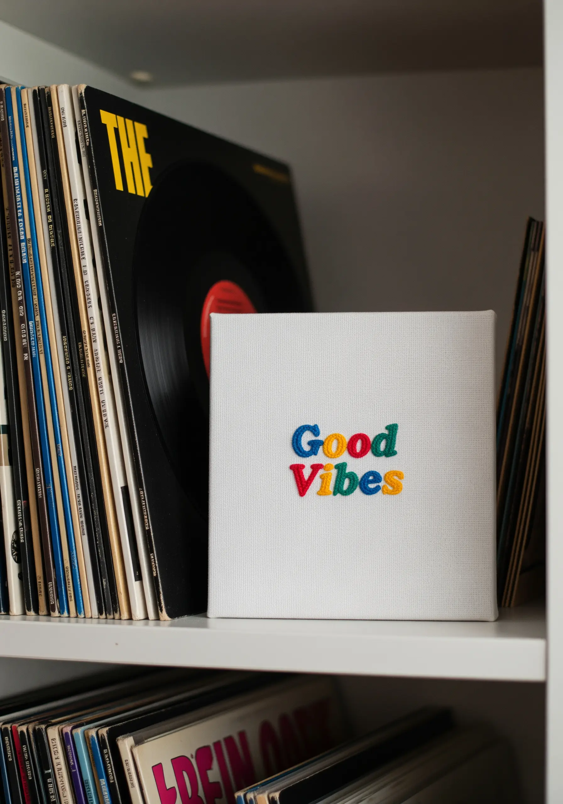 The words 'Good Vibes' embroidered in colorful, chunky lettering on a white canvas.