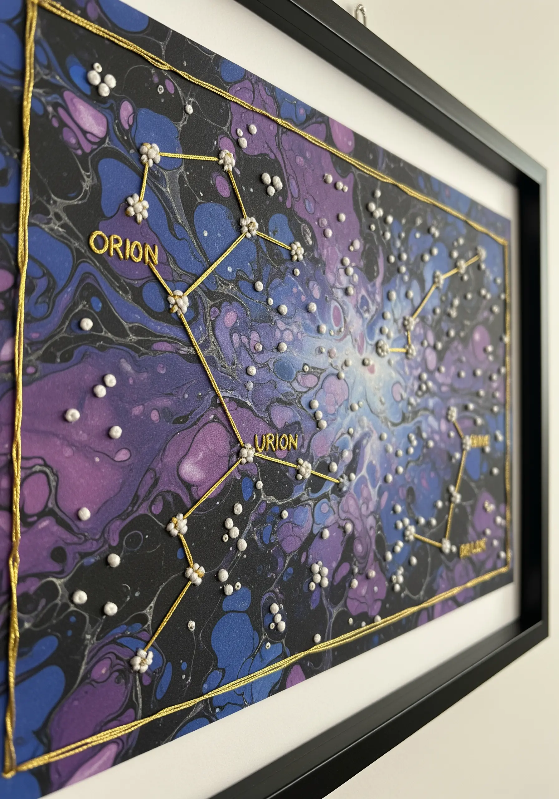 Embroidered constellations with gold thread and white beads on a purple and blue painted canvas.