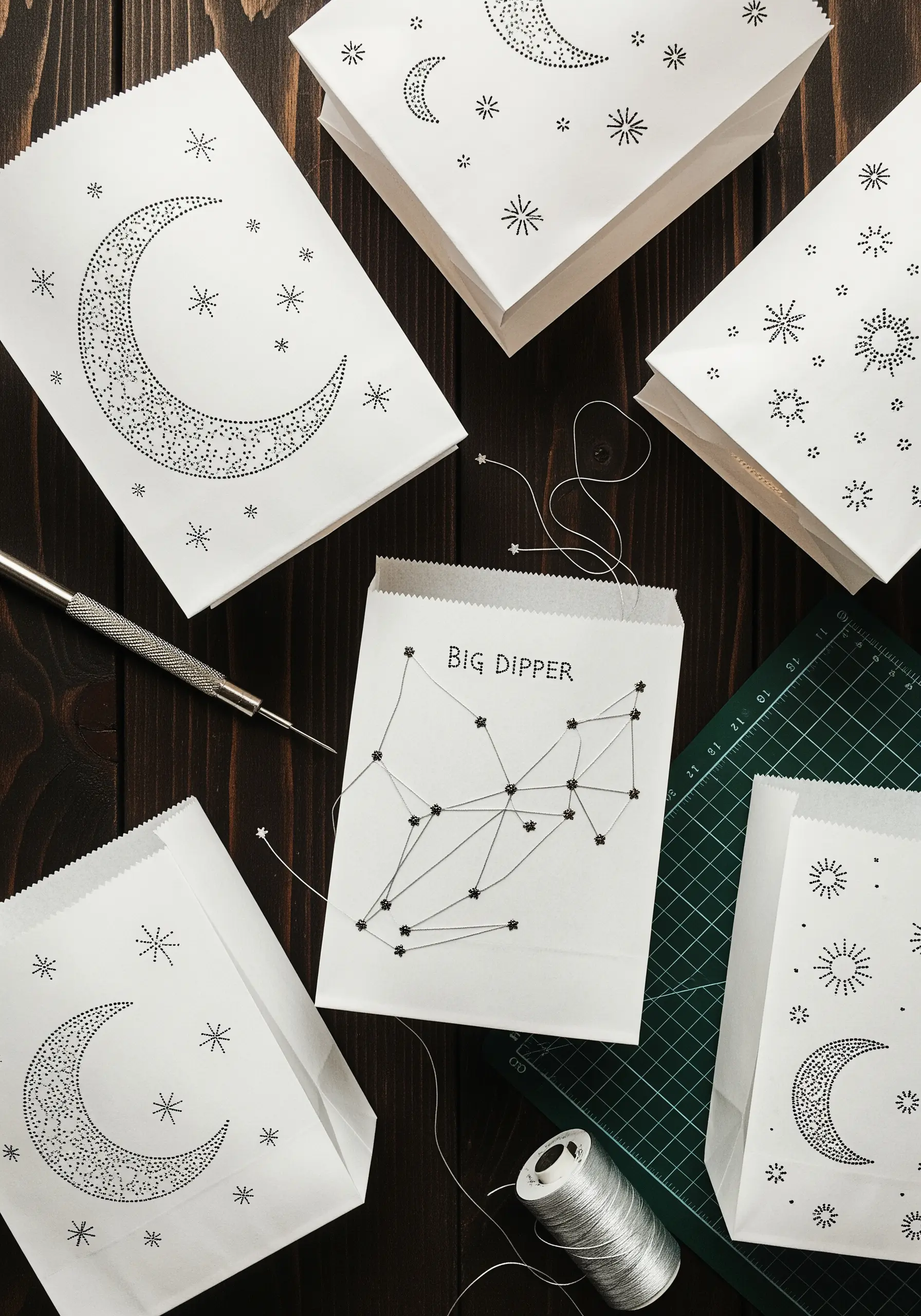 White paper bags decorated with constellations and moons stitched directly onto the paper with thread.