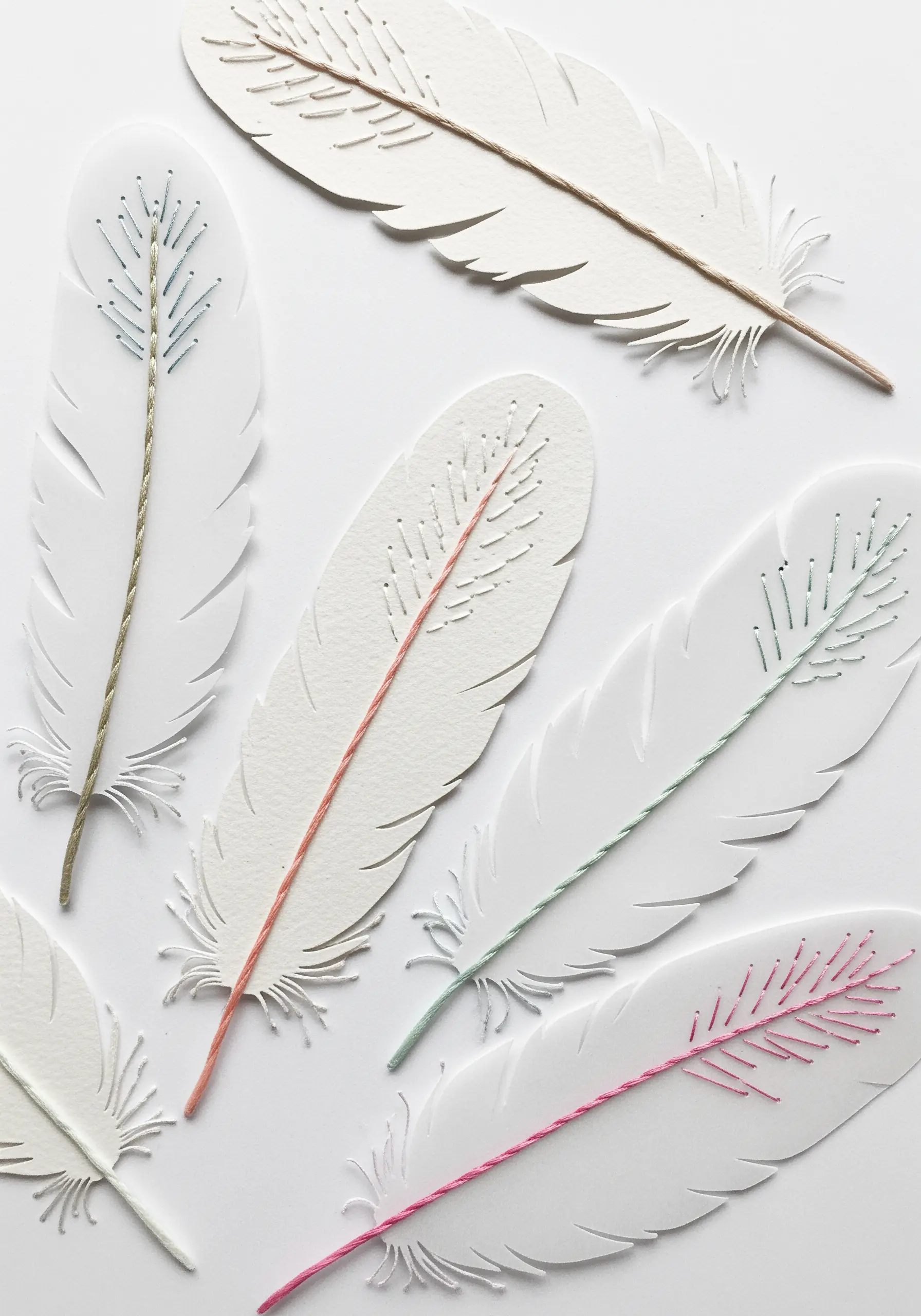 White paper feathers with delicate, colorful stitches for the veins and quill.