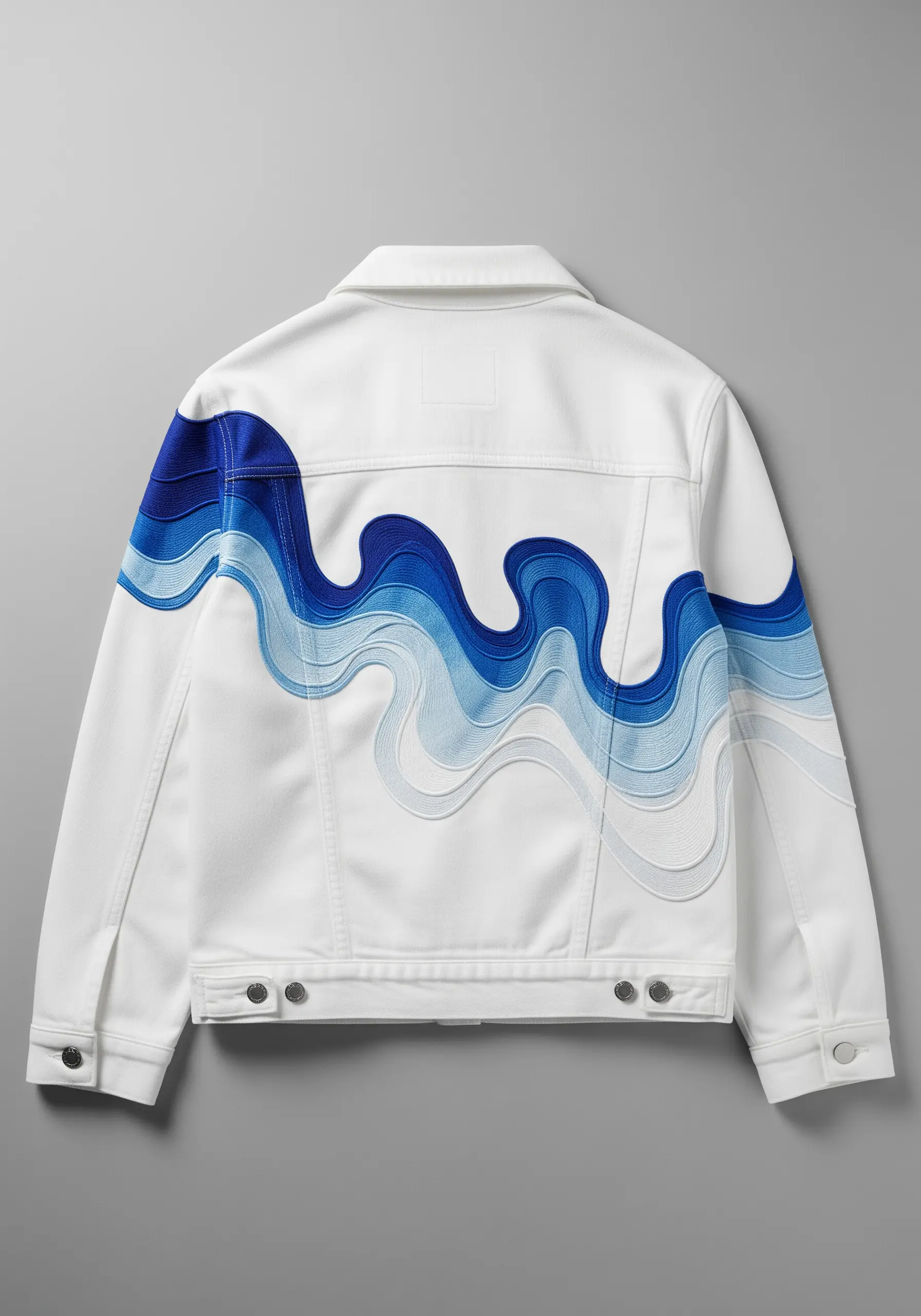 Flowing blue and white embroidered waves across the back of a white denim jacket.
