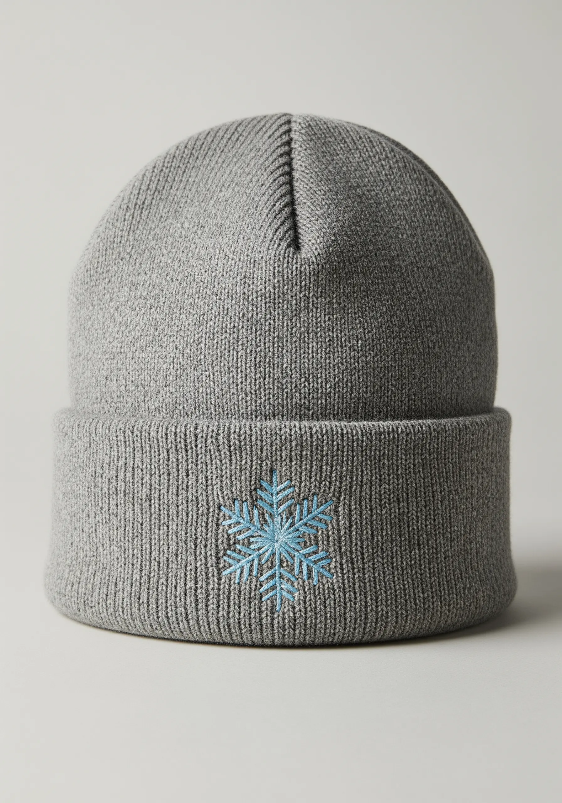 A light blue snowflake embroidered on the cuff of a grey knit beanie.