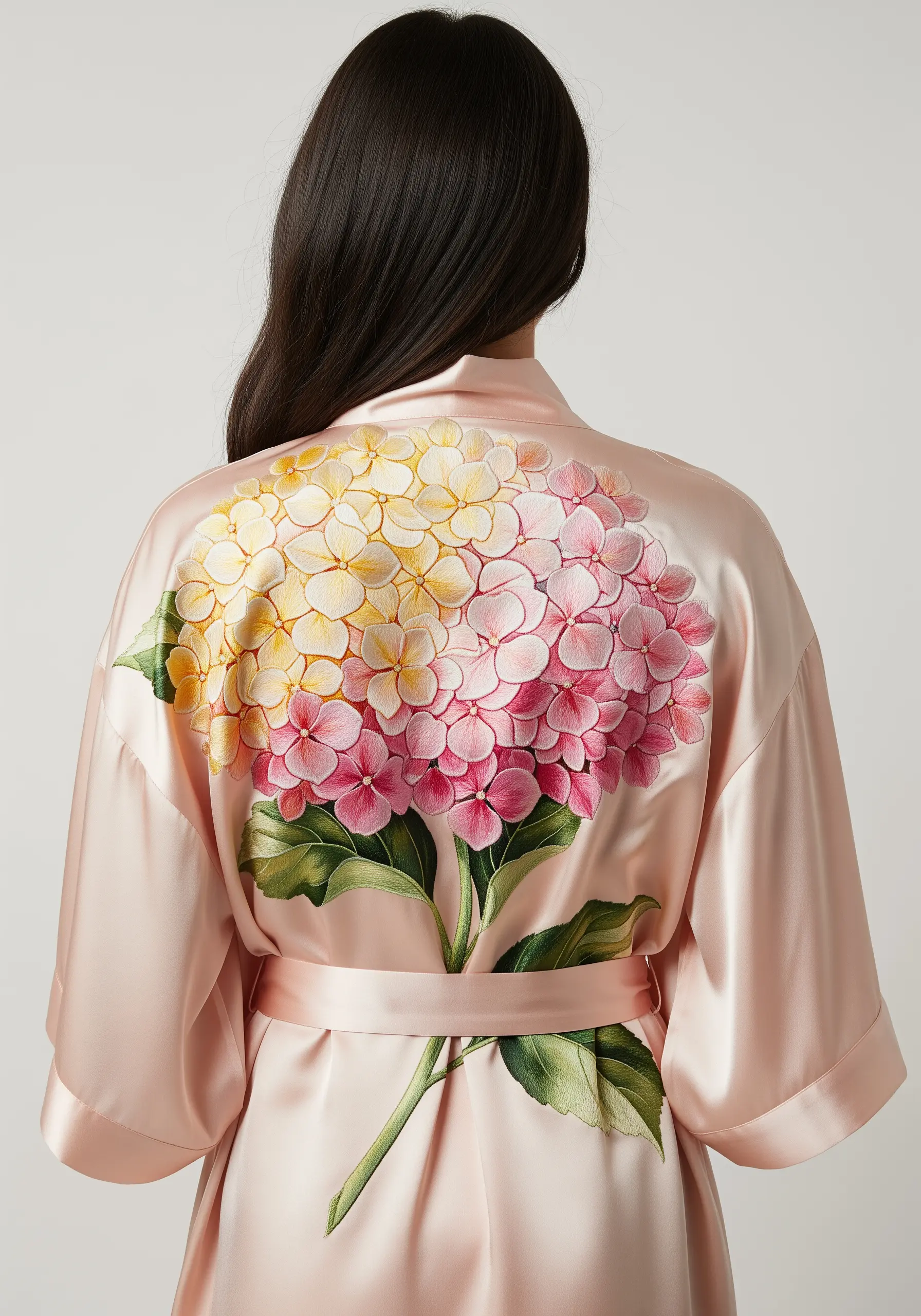 A large pink and yellow hydrangea embroidered across the back of a pink silk robe.