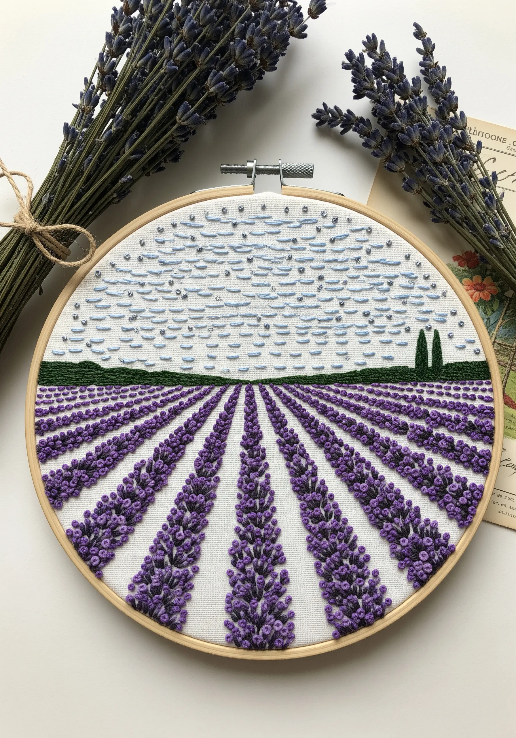 Embroidery of a lavender field with rows leading to the horizon line.