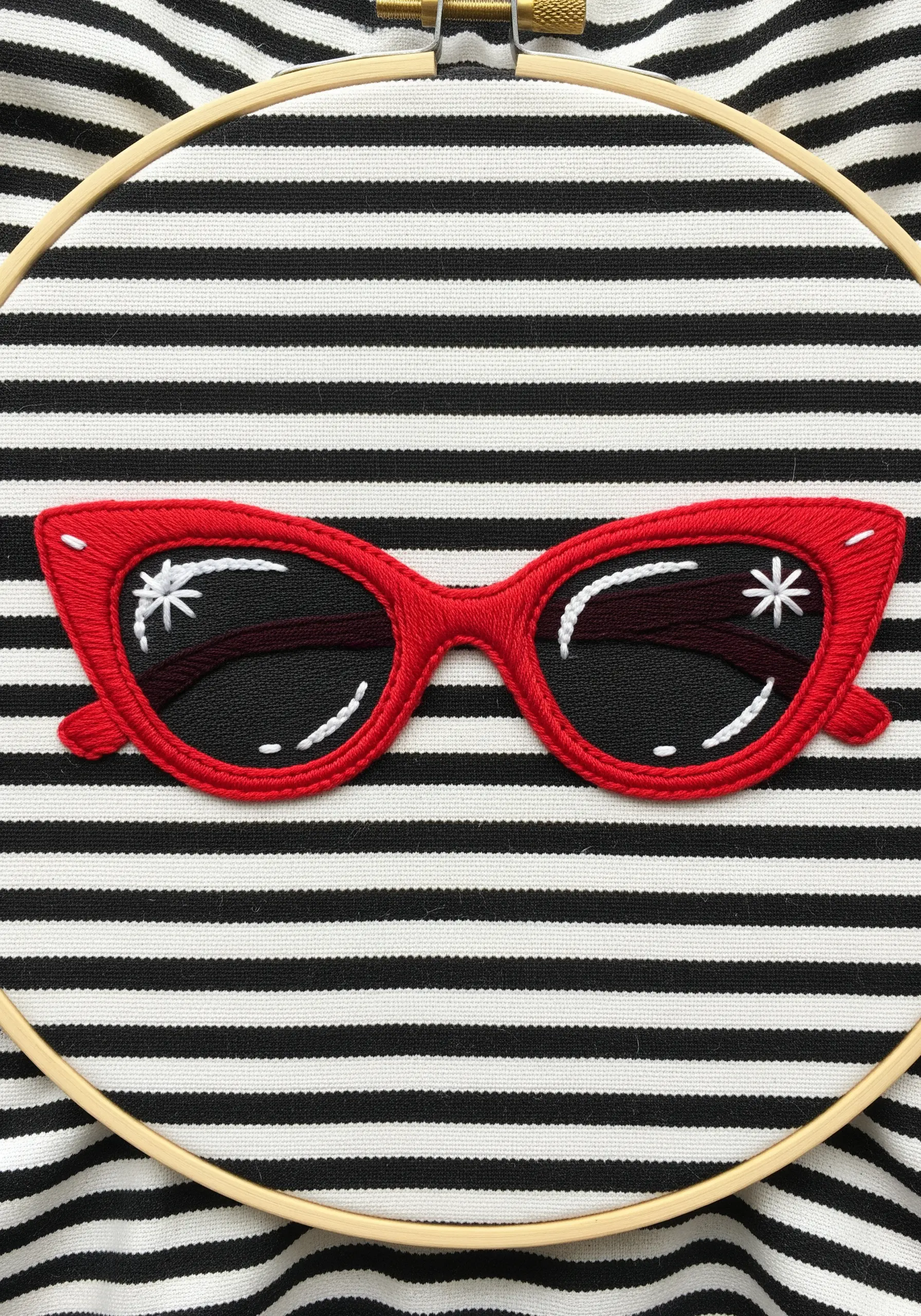 Red cat-eye sunglasses embroidered on striped fabric with stitched white reflections.