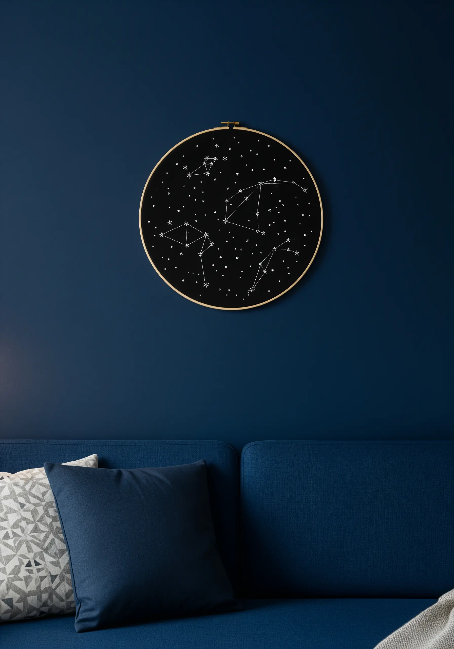 An embroidery hoop with white-stitched constellations on a dark blue background