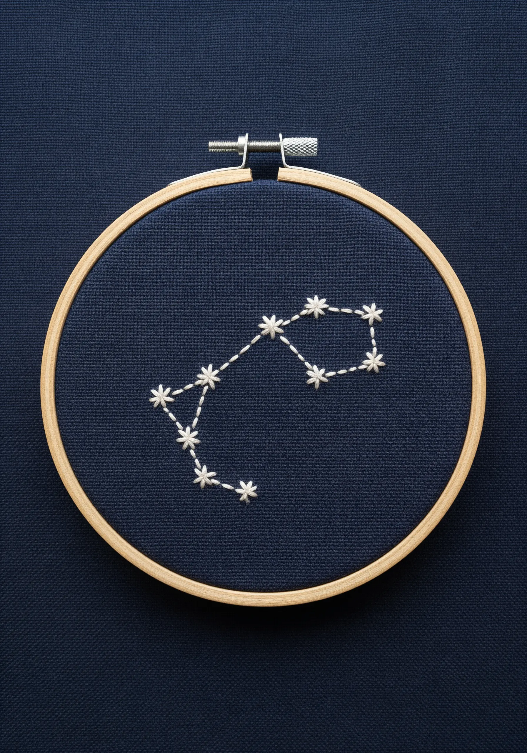 Embroidered Scorpio constellation with white lazy daisy stitches on dark blue fabric.