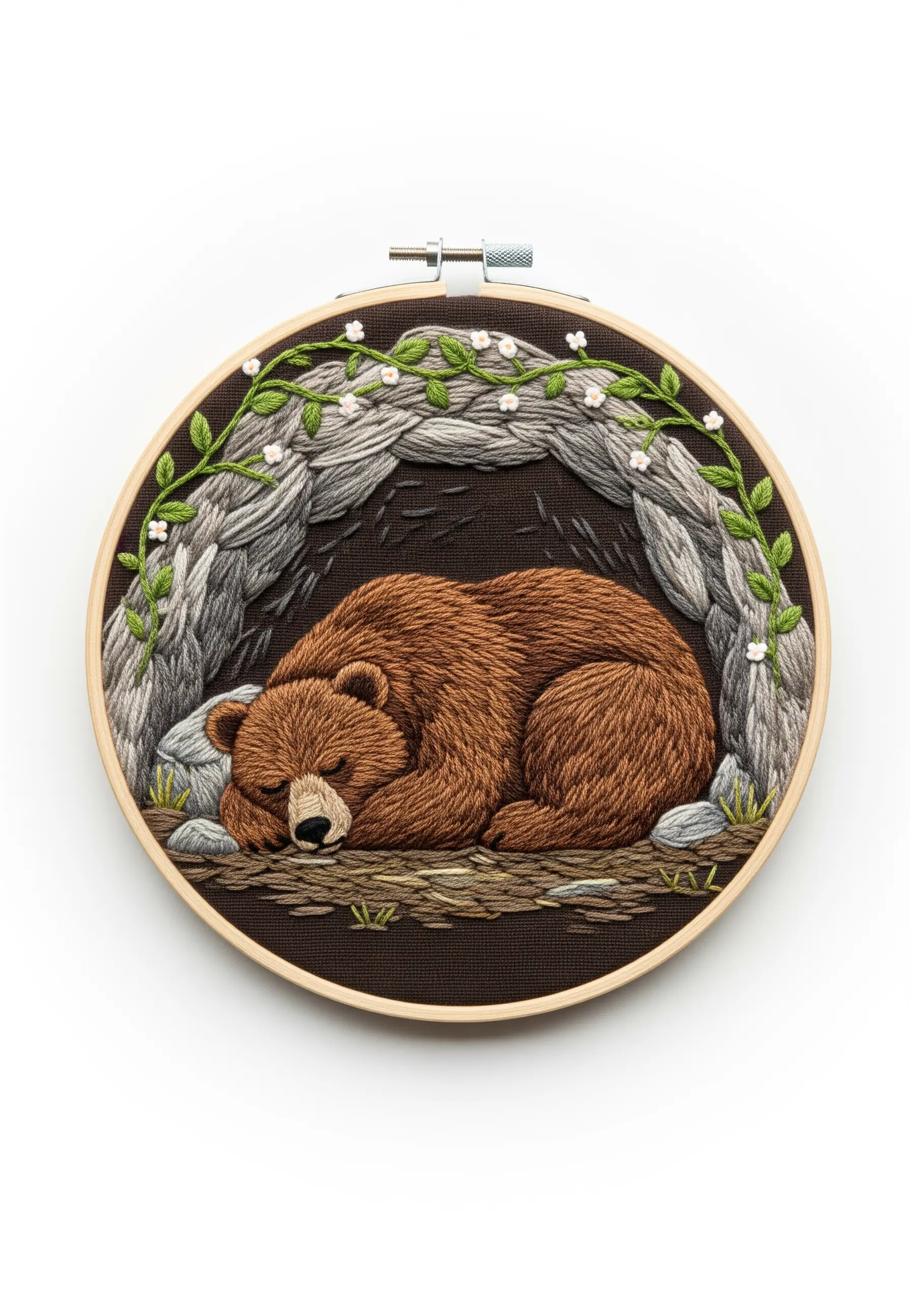 Embroidered sleeping bear in a cave with textured long-and-short stitch rocks.