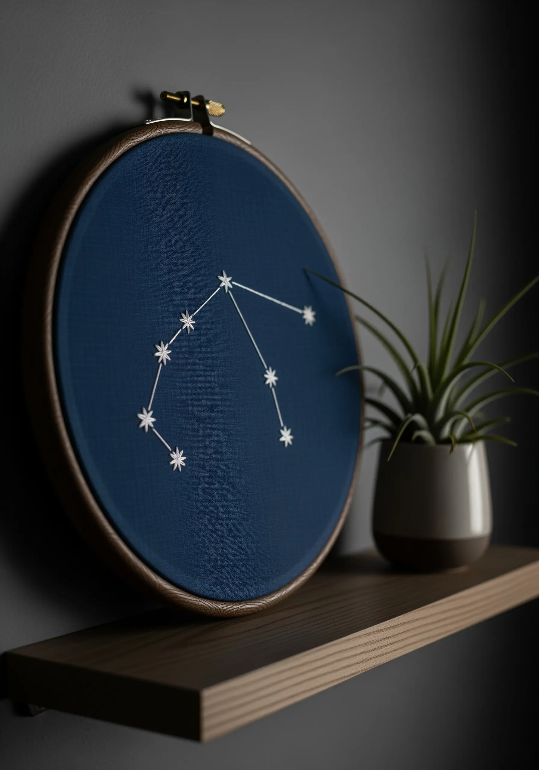 Embroidered Aquarius constellation on dark blue fabric in a hoop.