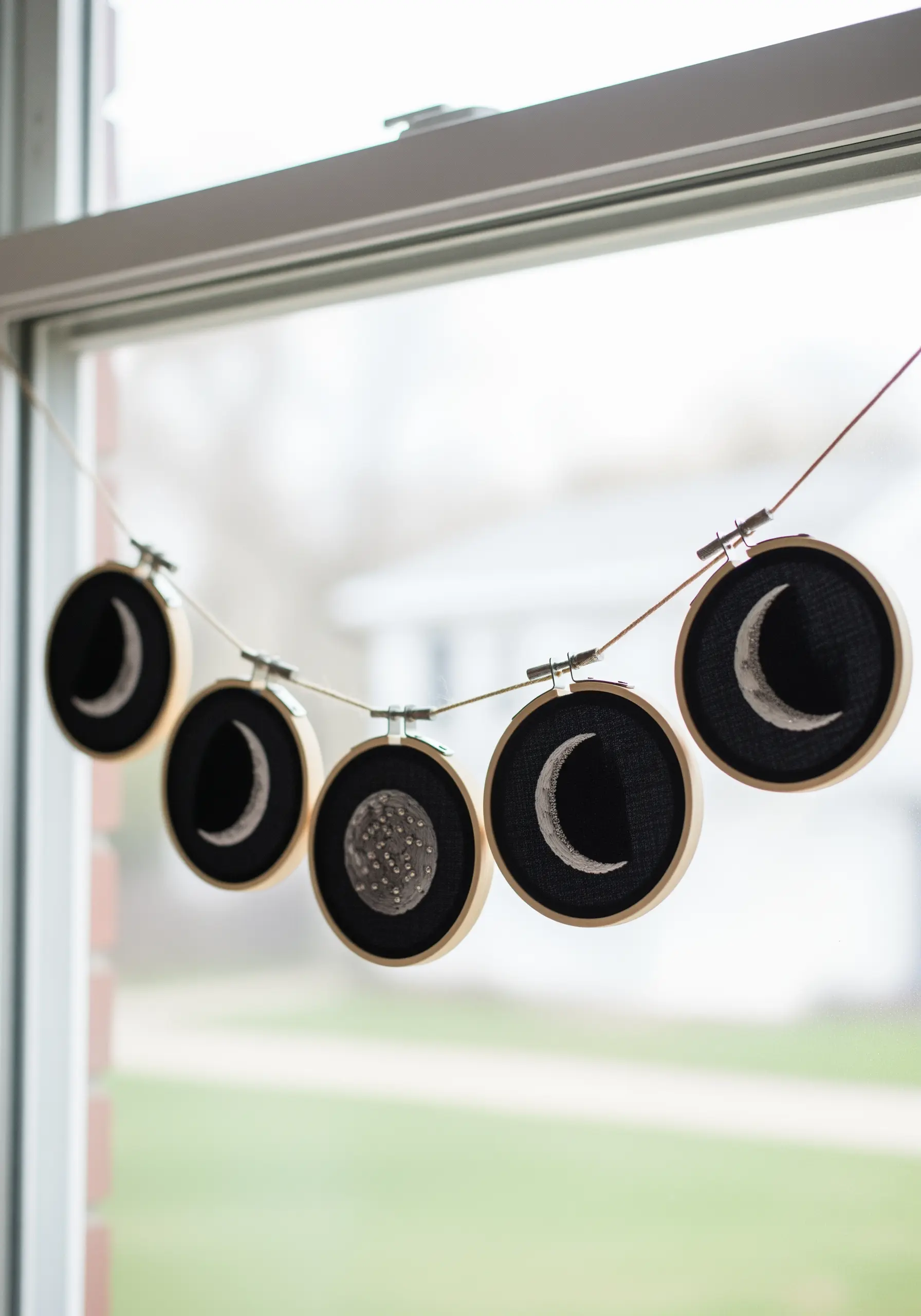 A garland of small embroidery hoops showing the different phases of the moon.