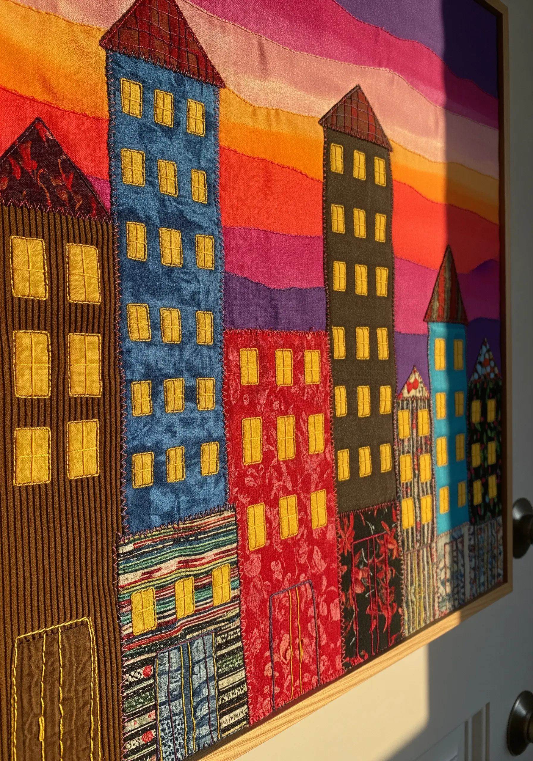 A vibrant fabric collage of a cityscape made from different textured and colored materials.