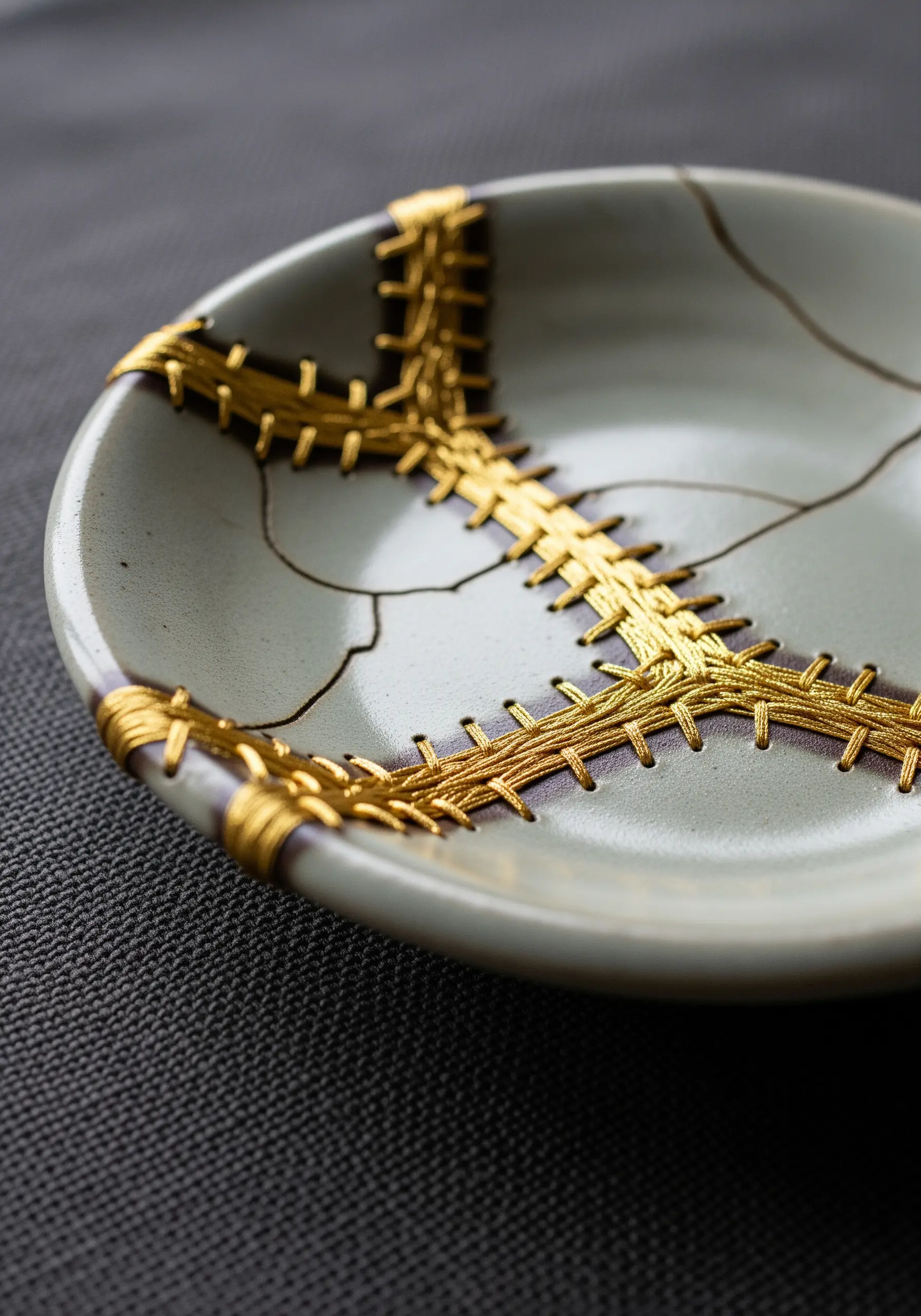 A cracked ceramic bowl repaired with gold thread in the style of Kintsugi.