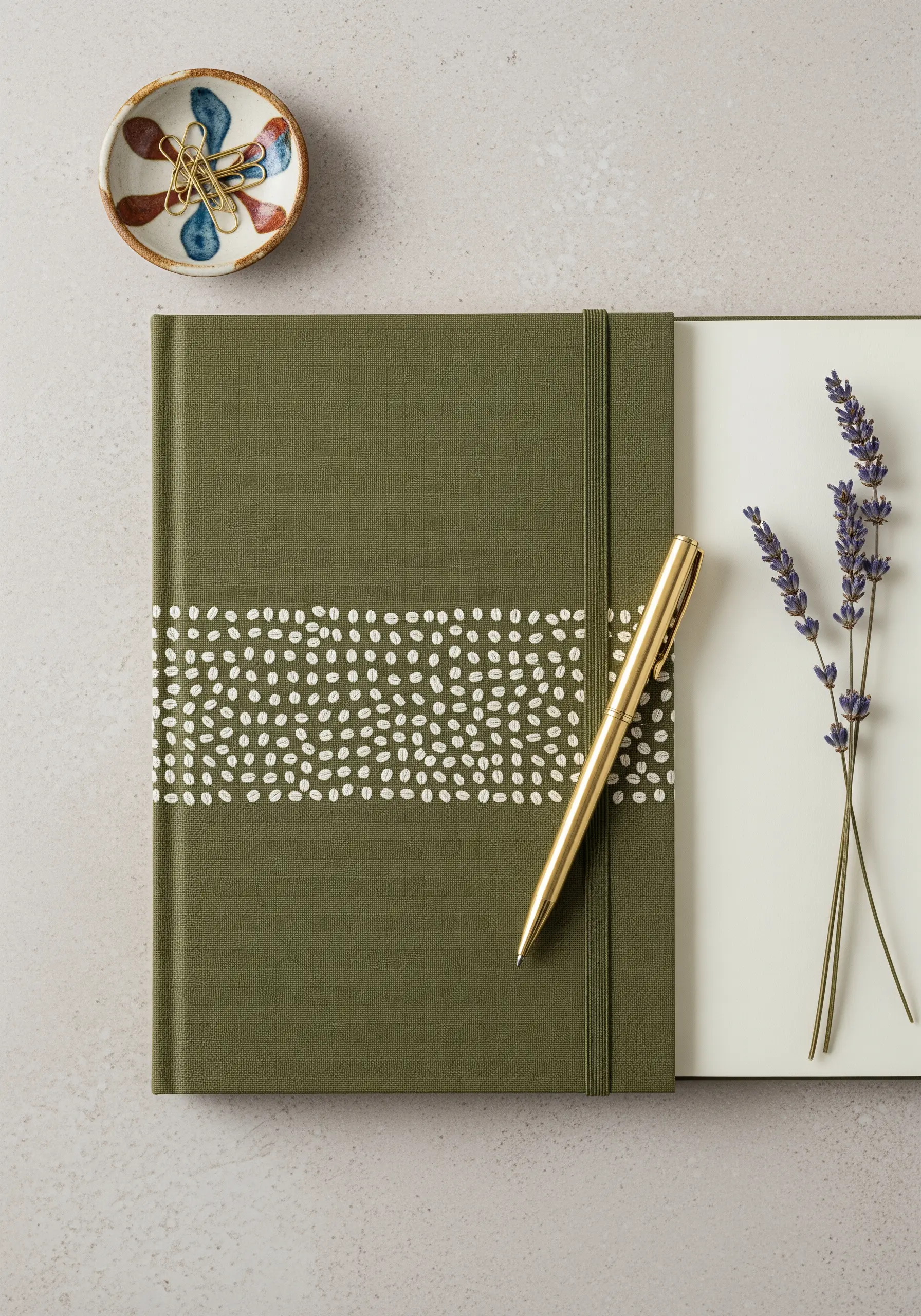 A dense band of scattered white seed stitches across the cover of an olive green notebook.