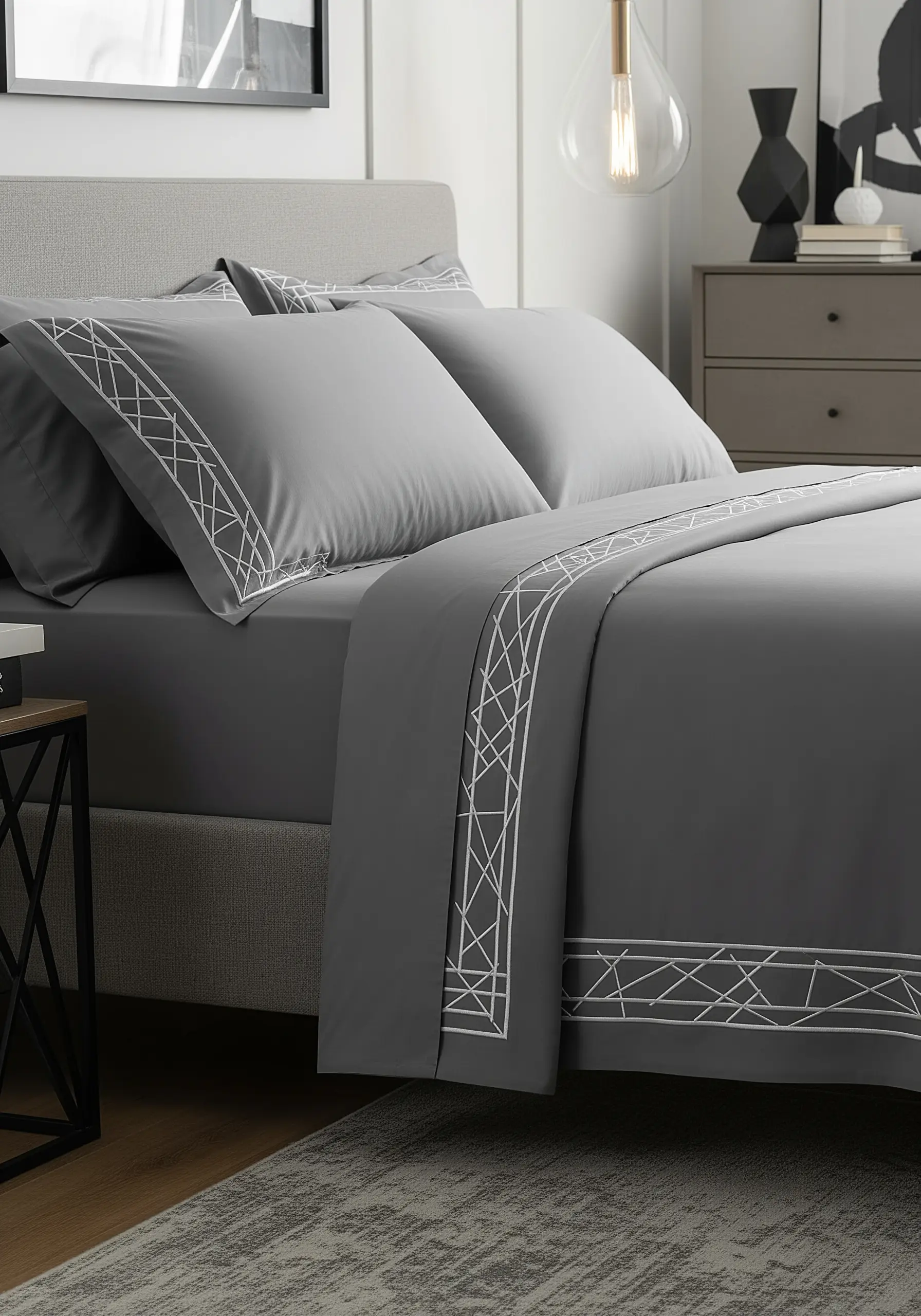 A high-contrast white geometric Art Deco border on dark grey bedsheets.