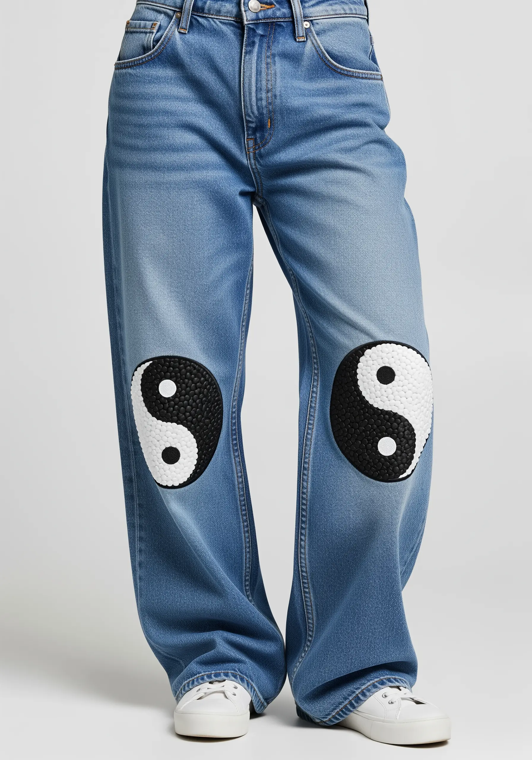 Yin-yang symbols embroidered with black and white beads on the knees of jeans.