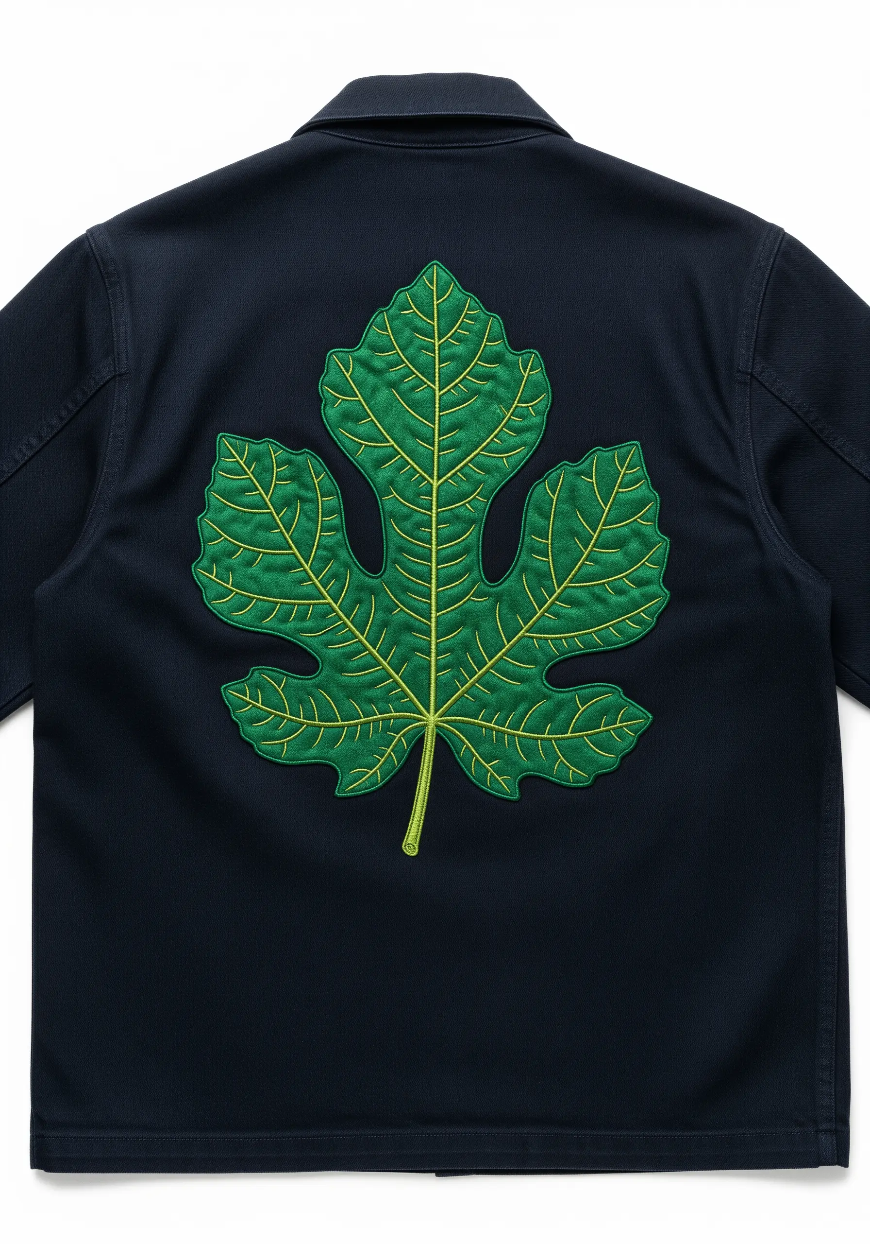 A large green fig leaf embroidered patch with yellow veins on a navy jacket.