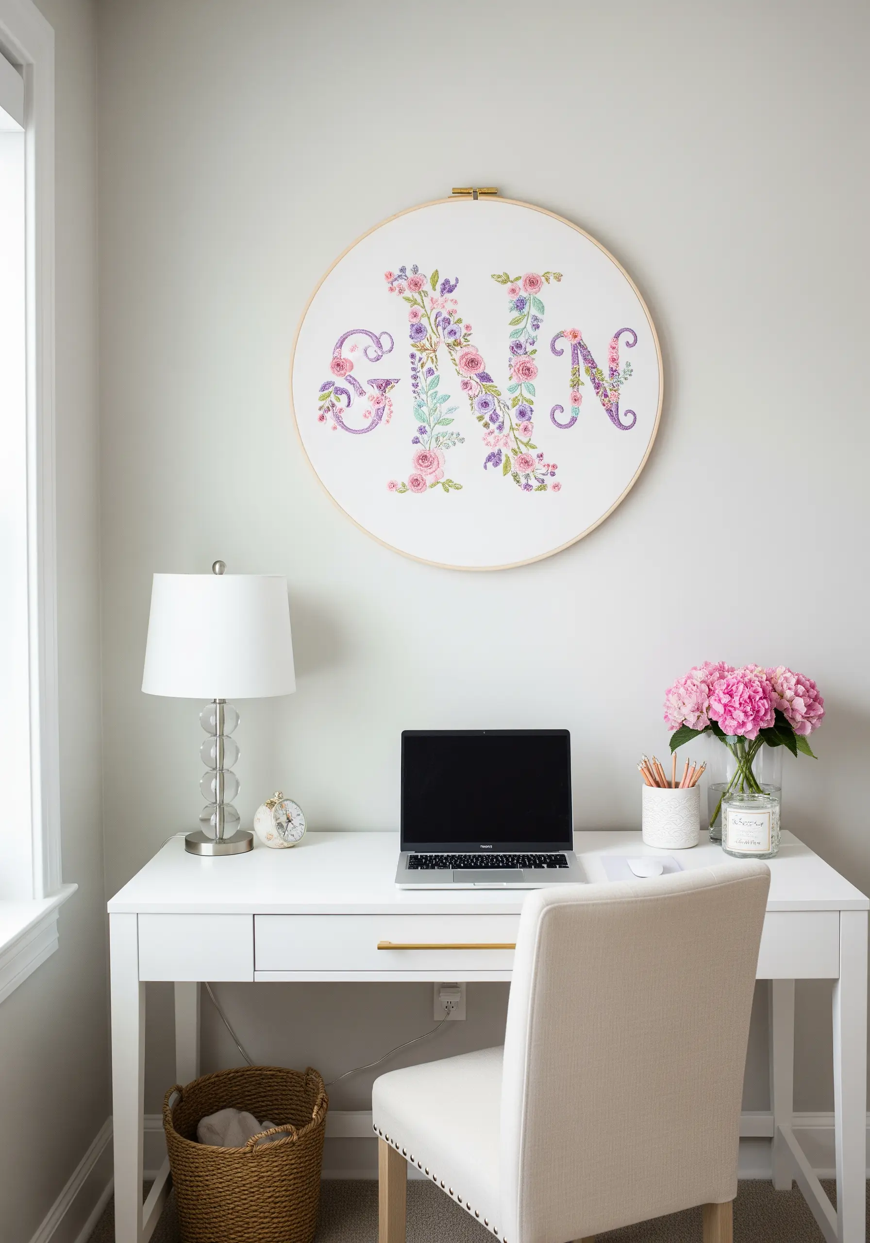 A large embroidery hoop with the letter 'N' formed from delicate floral embroidery.