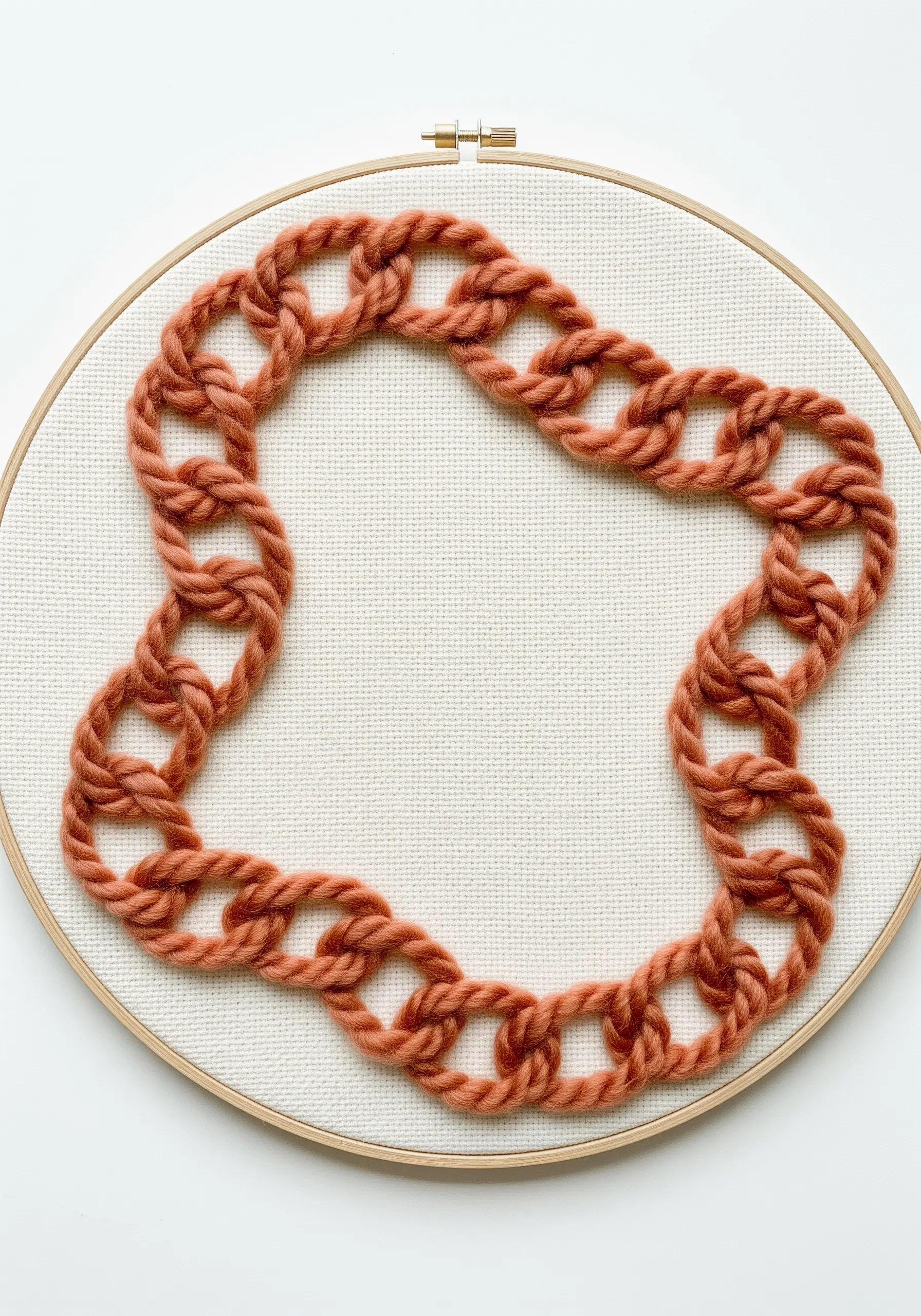 A chunky, open chain stitch embroidered with terracotta-colored yarn on off-white fabric.