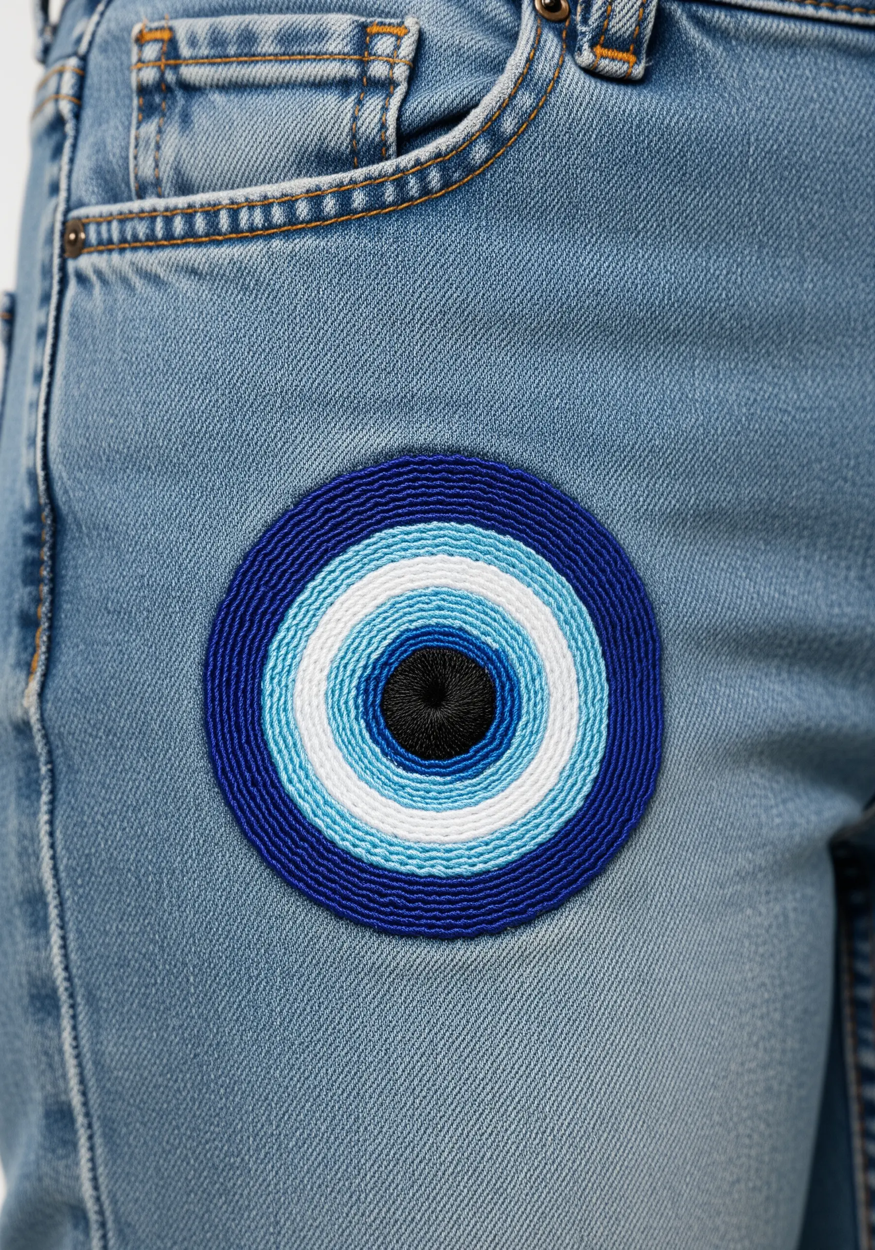 A circular evil eye (nazar) embroidered in concentric rings of blue, white, and black.