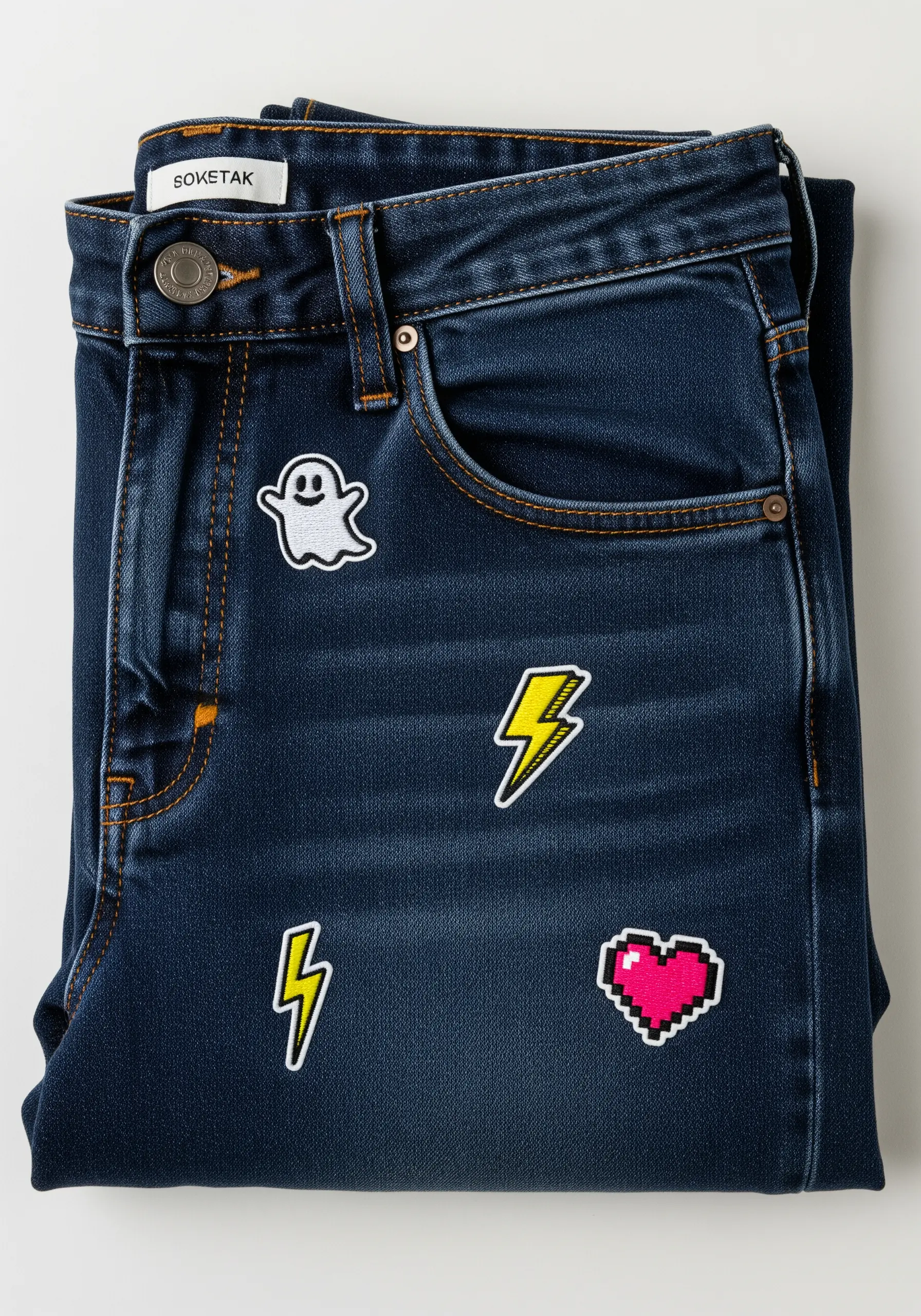 A collection of small embroidered patches—ghost, lightning bolts, pixel heart—on dark denim.