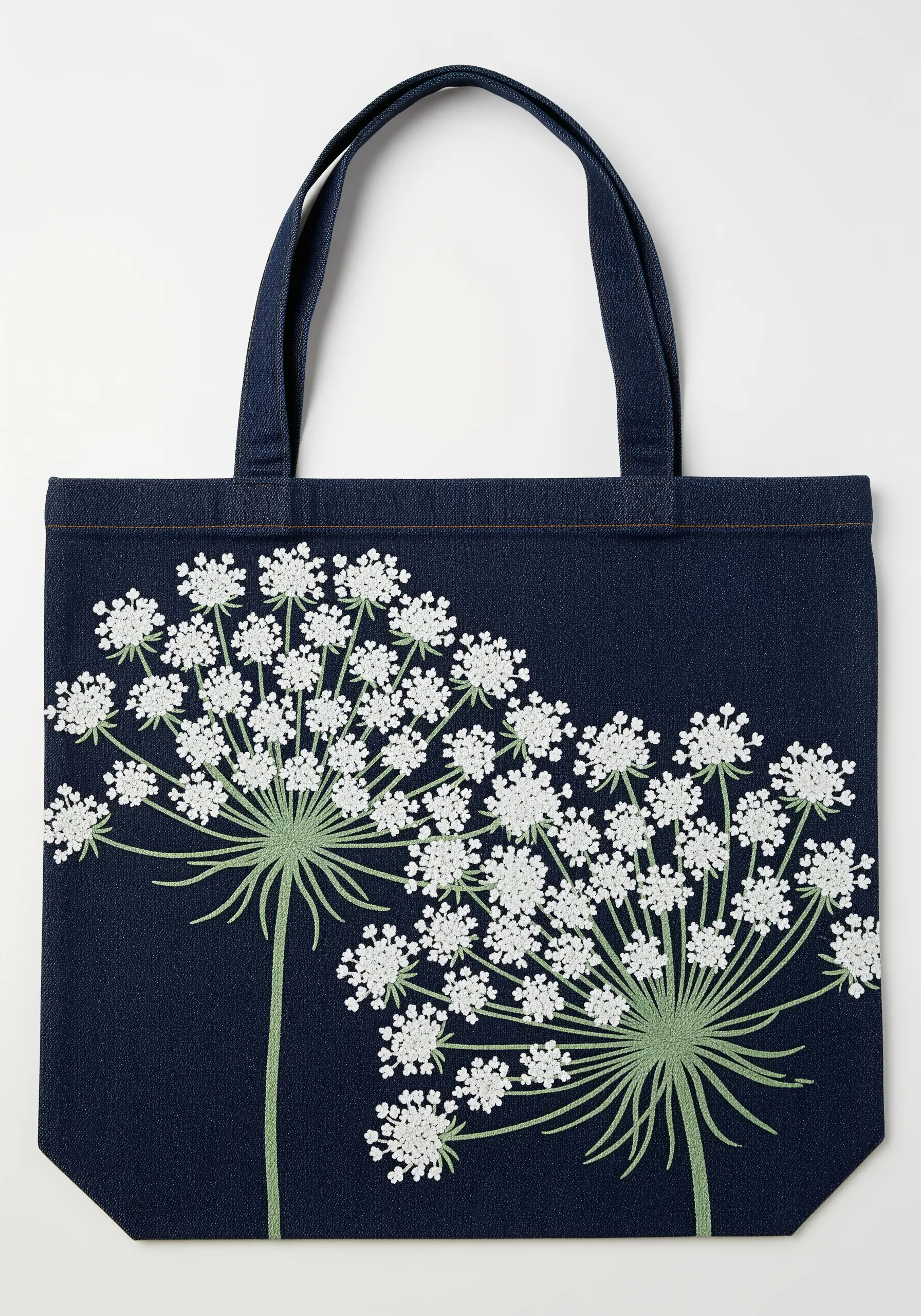 Intricate embroidery of Queen Anne's Lace flowers with French knots on a dark denim tote.