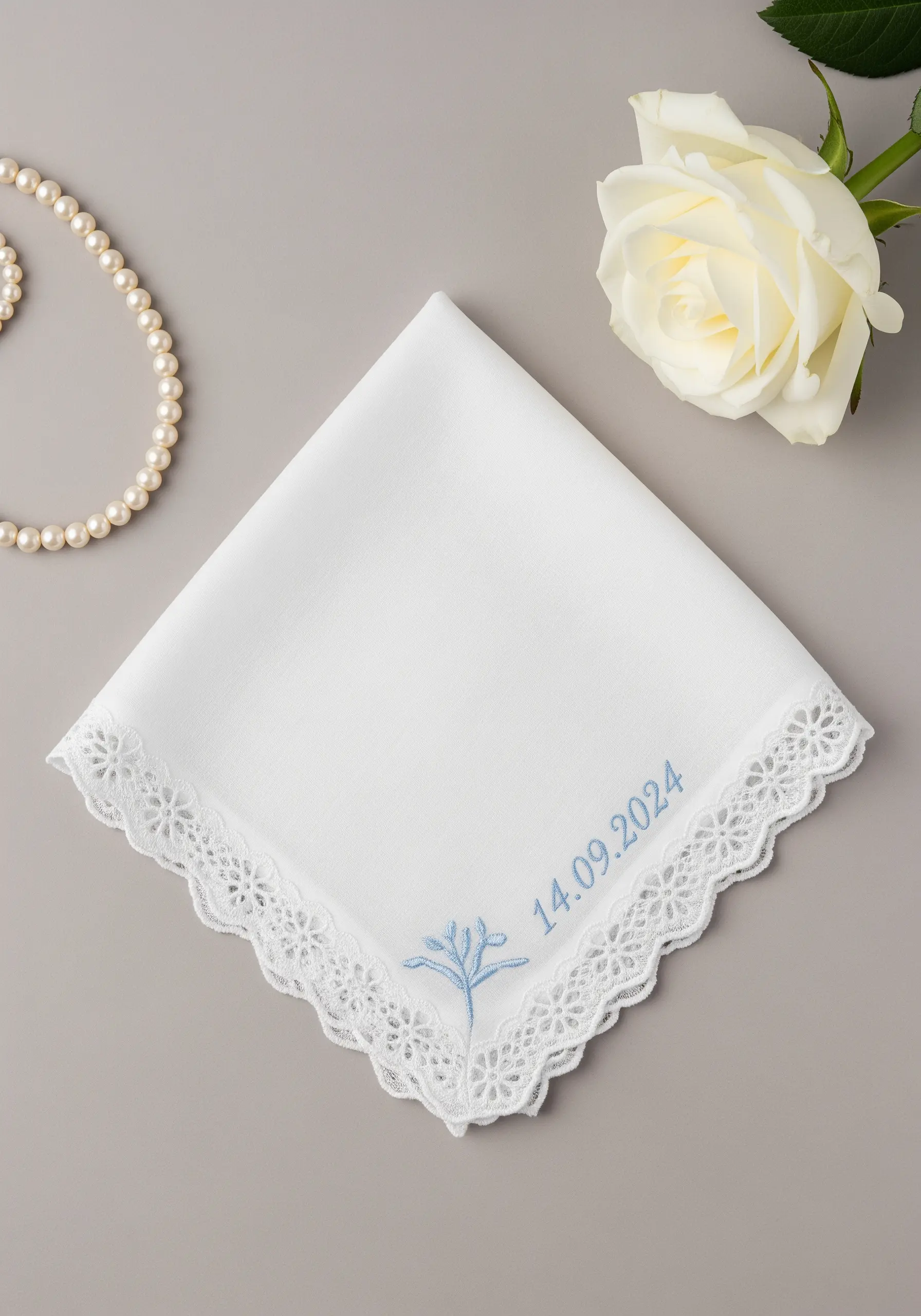 White lace-edged handkerchief with a light blue embroidered date and motif.