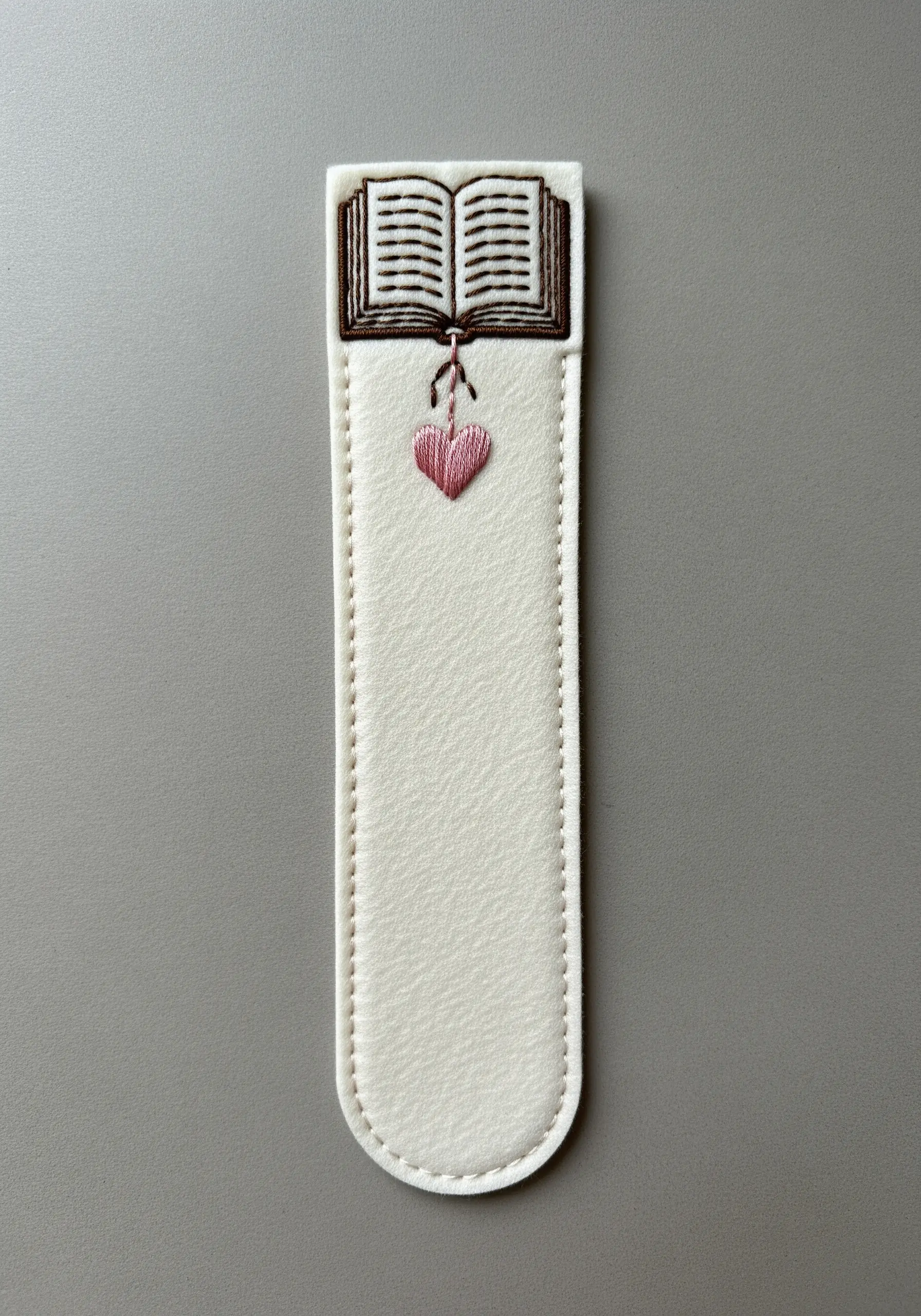 A hand-embroidered bookmark made of felt with a tiny open book and heart.