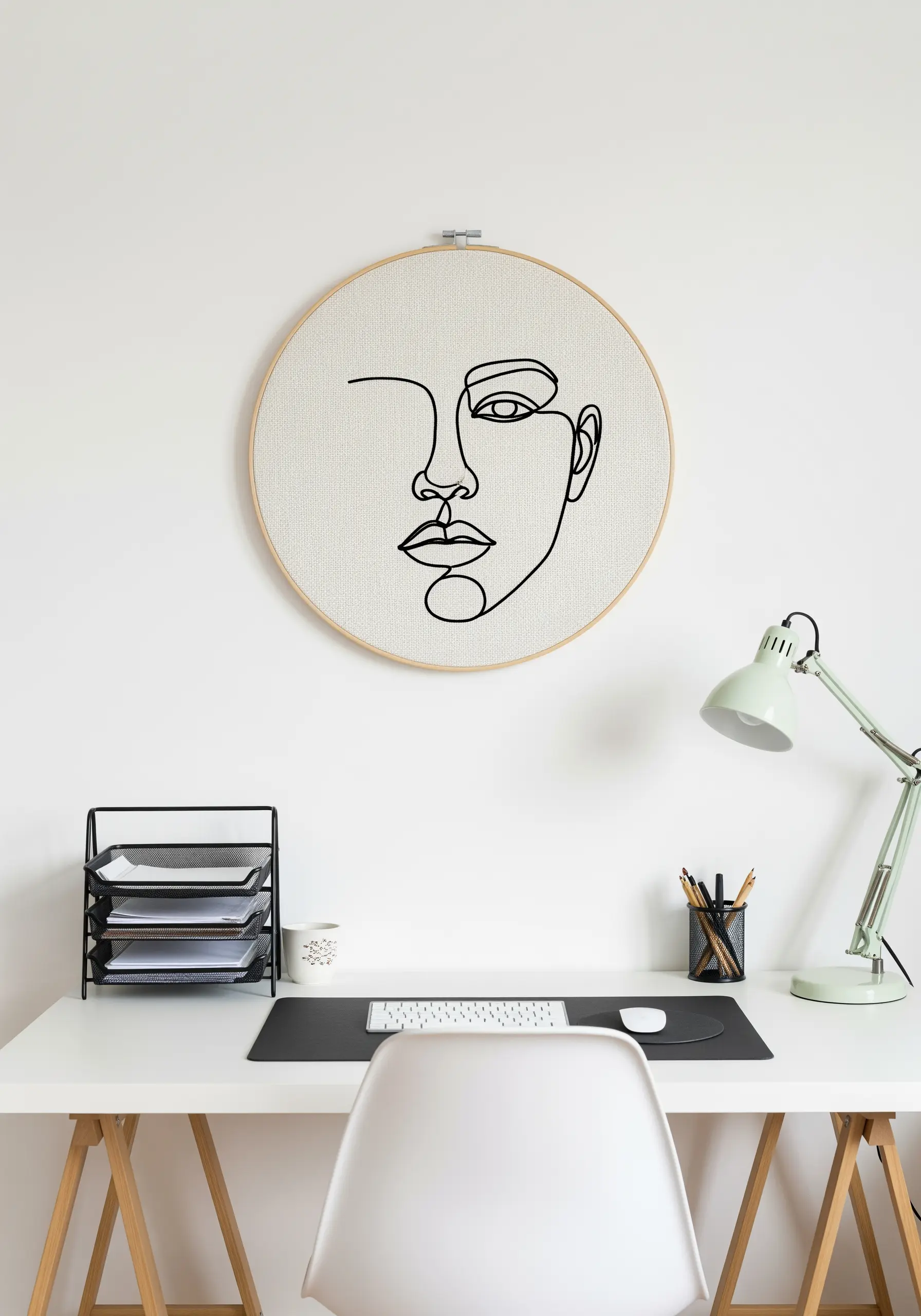 Minimalist line art face embroidered in black thread on a neutral background.