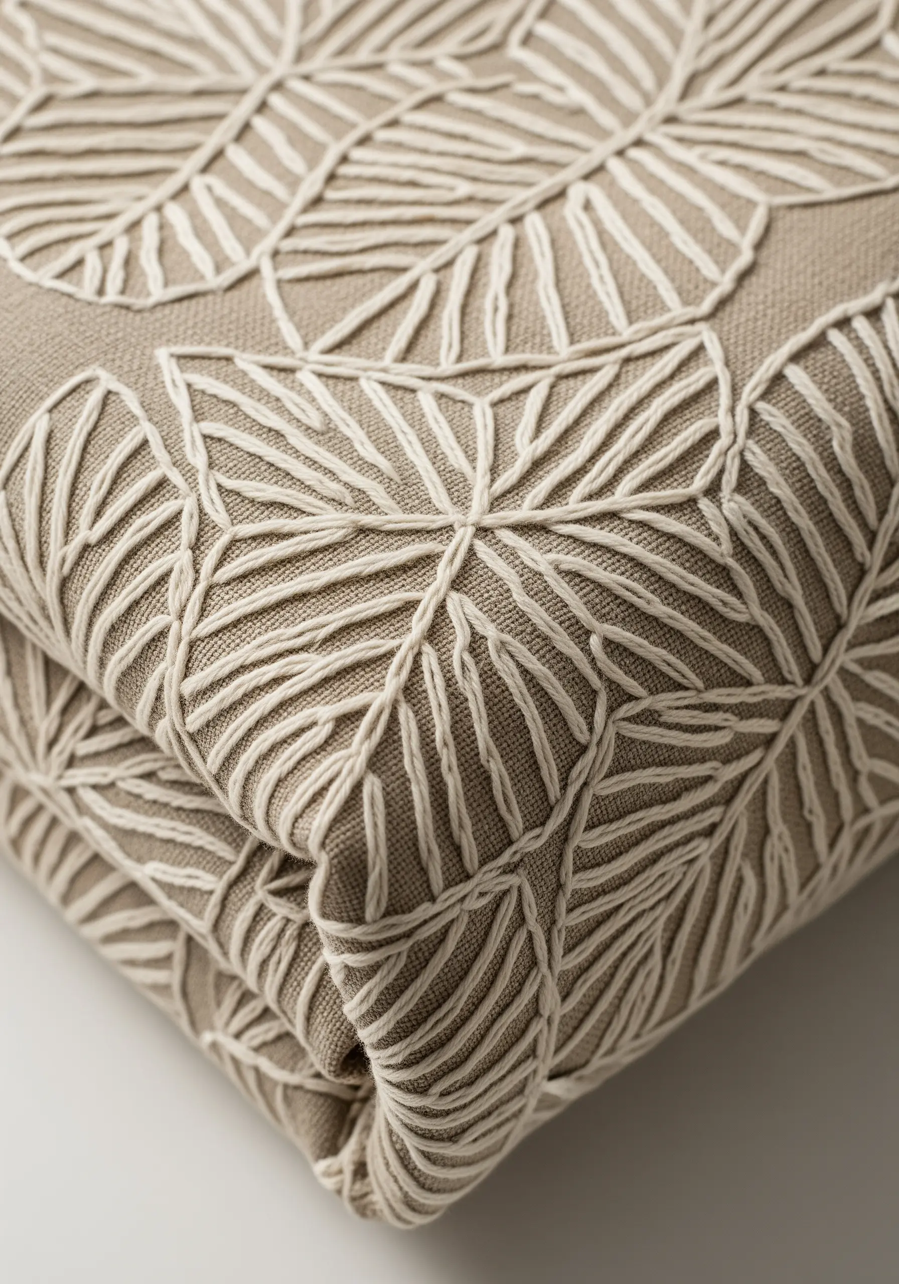 A repeating pattern of leaf outlines embroidered in off-white thread on a neutral linen fabric.