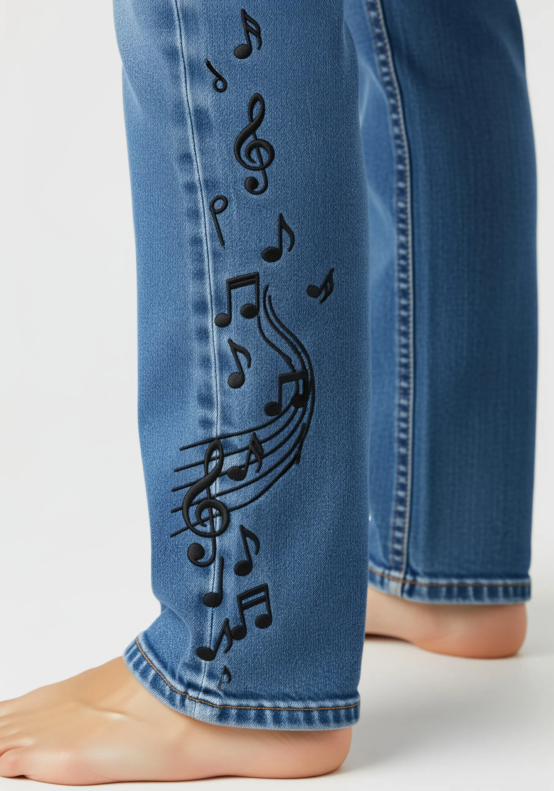 Black embroidered music notes flowing down the side of a blue jean leg.