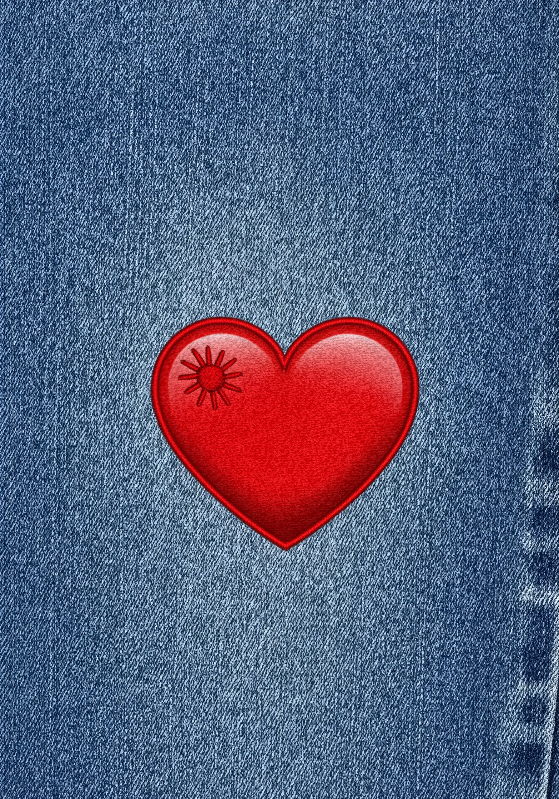 A single, glossy red heart embroidered on a medium-wash denim background.