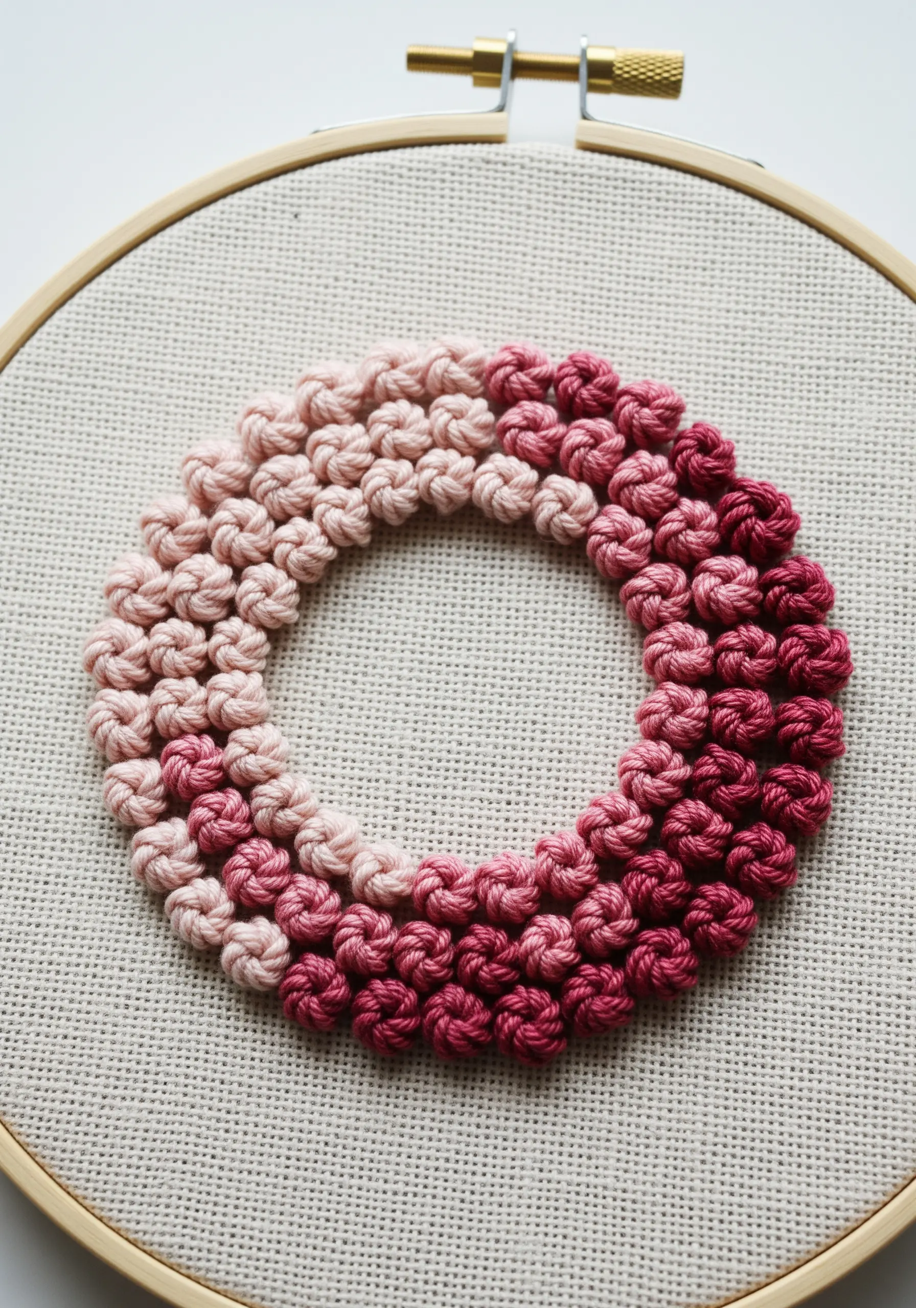 A circle of French knots transitioning from light pink to dark magenta.