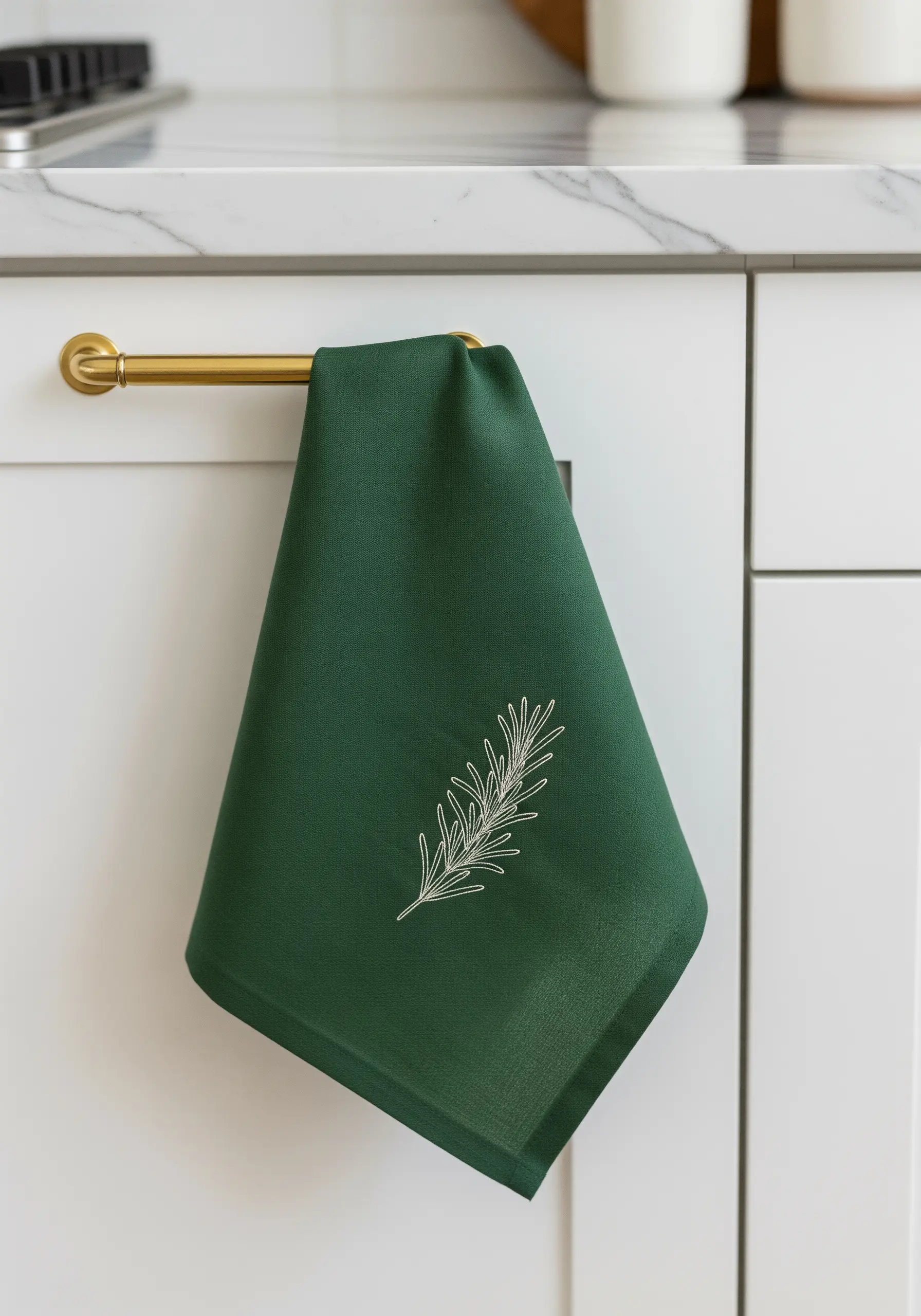 A single sprig of rosemary embroidered in white thread on a dark green tea towel.