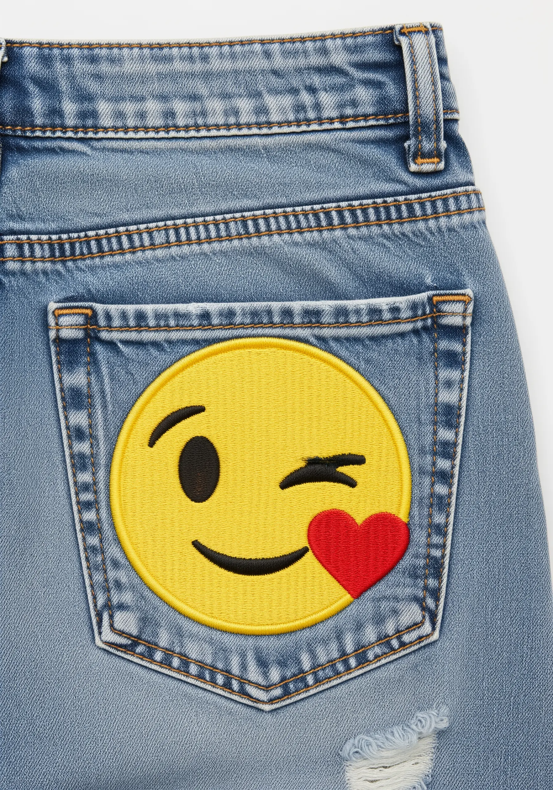 A smooth, satin-stitched winking kiss emoji patch embroidered on a denim pocket.