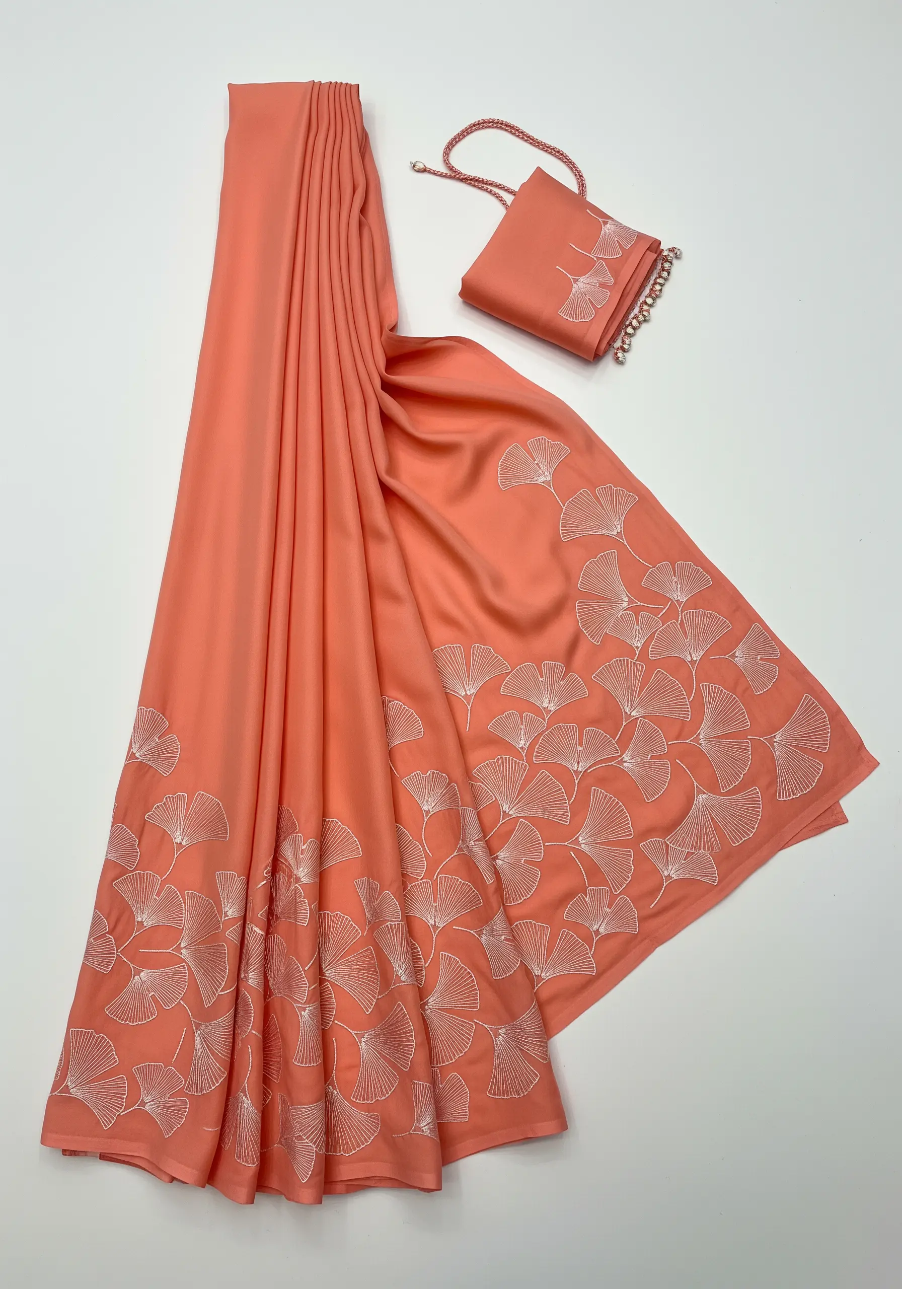 Overlapping white line-art ginkgo leaf embroidery on a coral scarf.