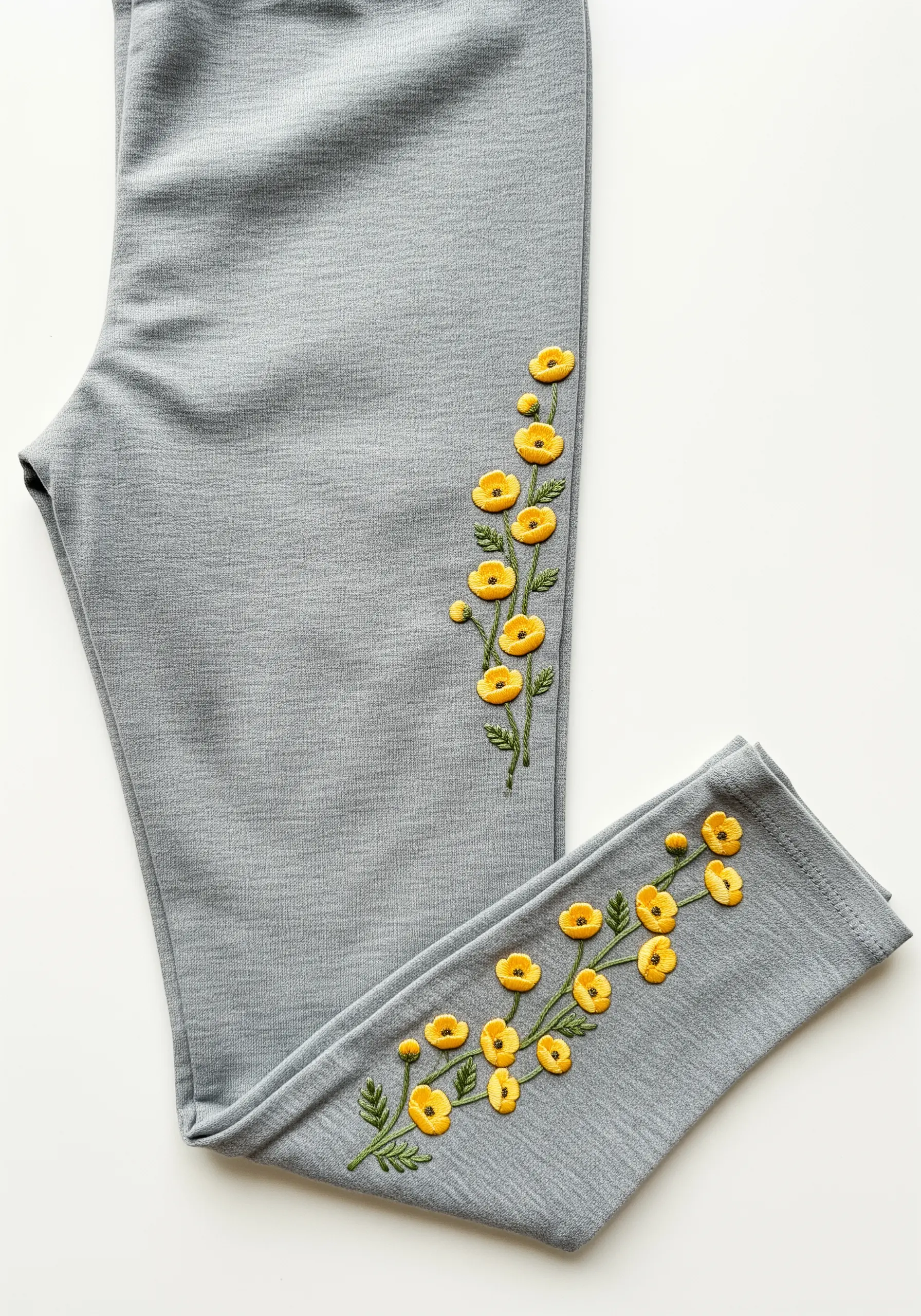 A delicate vine of yellow buttercups embroidered up the side of gray leggings.